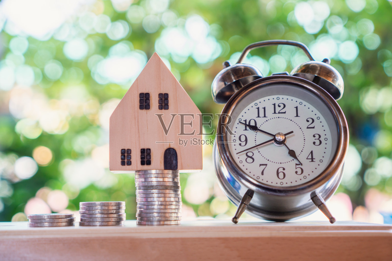 堆叠硬币时钟和房子模型,计划购买的家庭概念照片摄影图片