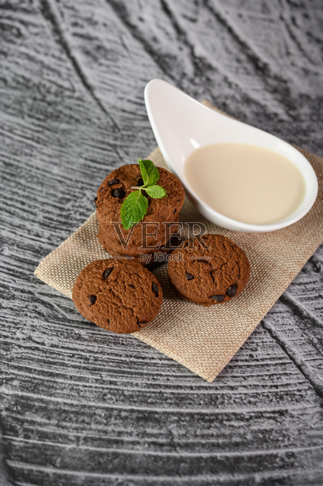 木桌上的一块布上放着一堆饼干和一勺牛奶照片摄影图片