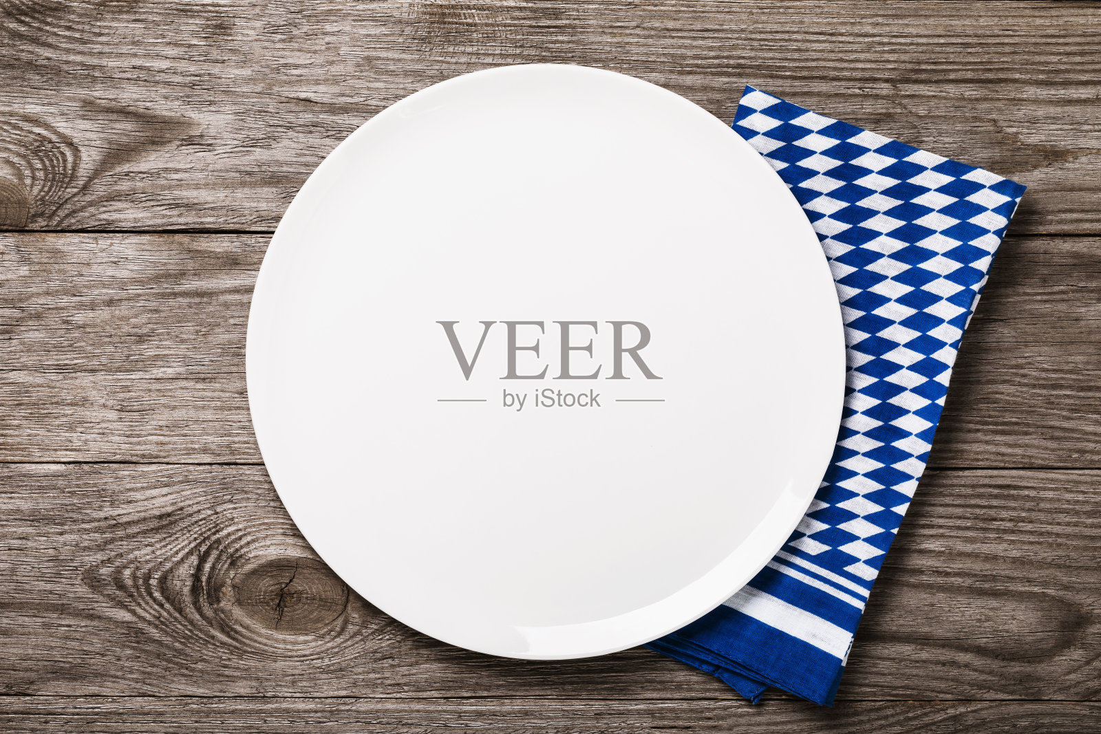 木桌上放着白色陶瓷托盘,上面放着巴伐利亚餐巾,俯视图。食品的背景照片摄影图片