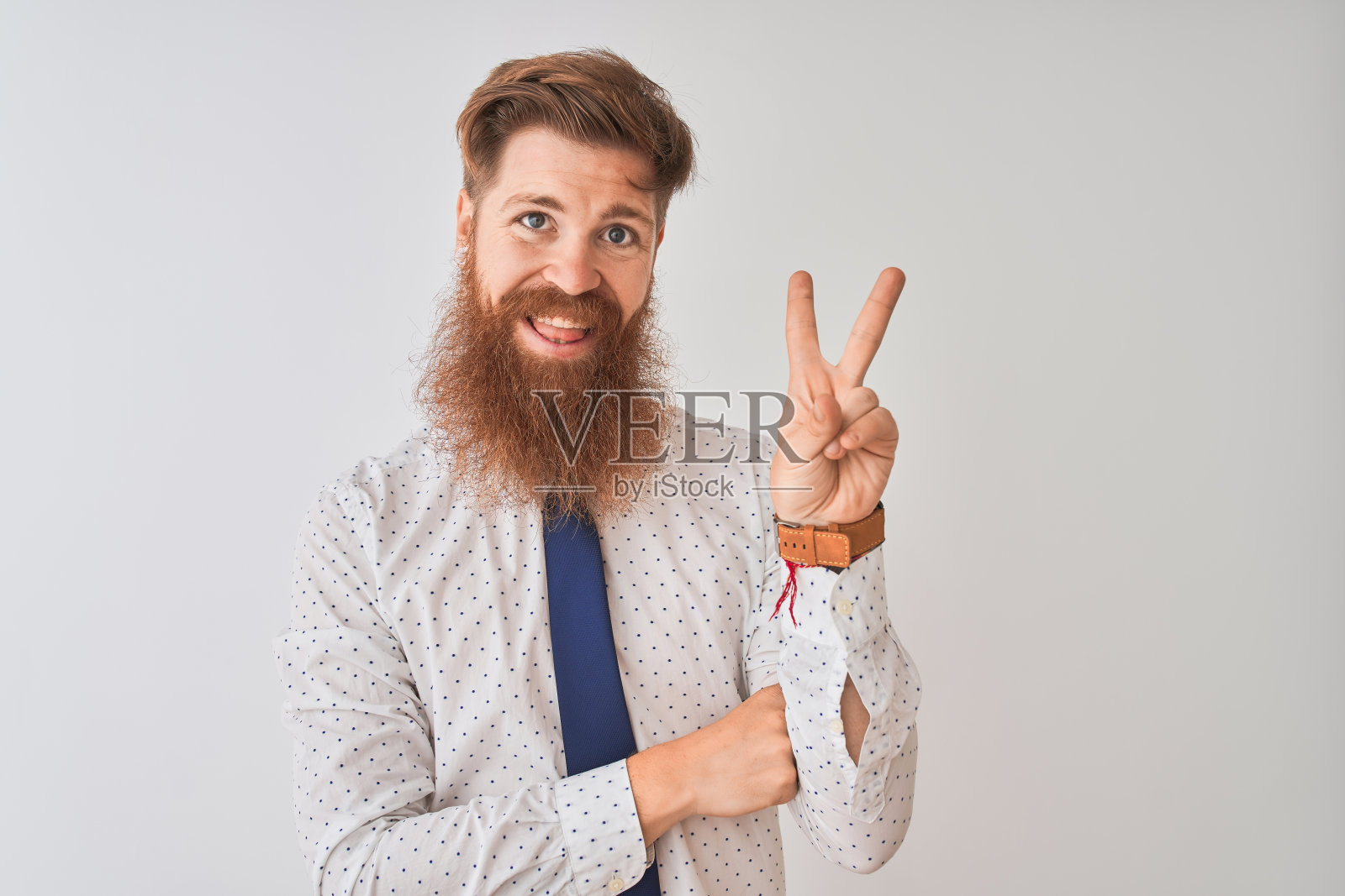 年轻的红头发的爱尔兰商人站在孤立的白色背景微笑与幸福的脸对着镜头眨着手指做胜利手势。二号人物。照片摄影图片