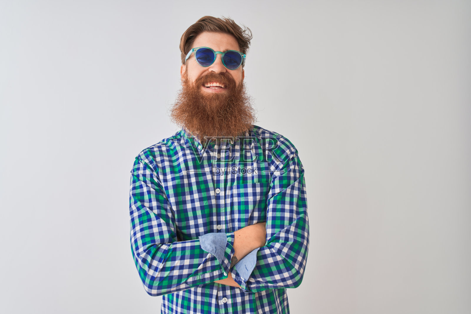 年轻的红发爱尔兰男子穿着休闲衬衫和太阳镜在孤立的白色背景快乐的脸微笑,双臂交叉看着镜头。积极的人。照片摄影图片