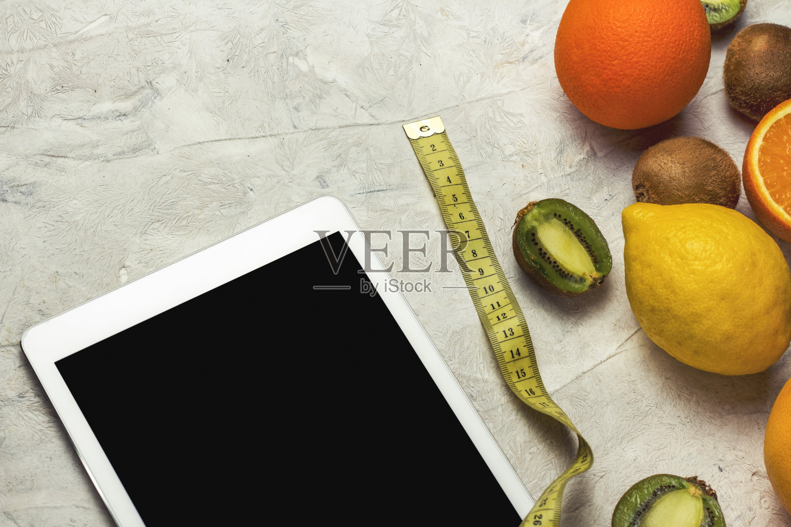 橘子,柠檬,猕猴桃,药片,测量卷尺的石头背景。减肥的概念。照片摄影图片