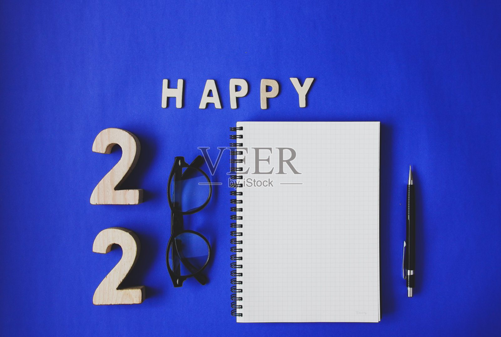庆祝改变2020年,用笔记本,老式的黑色眼镜和蓝色纸背景的铅笔新年快乐。照片摄影图片