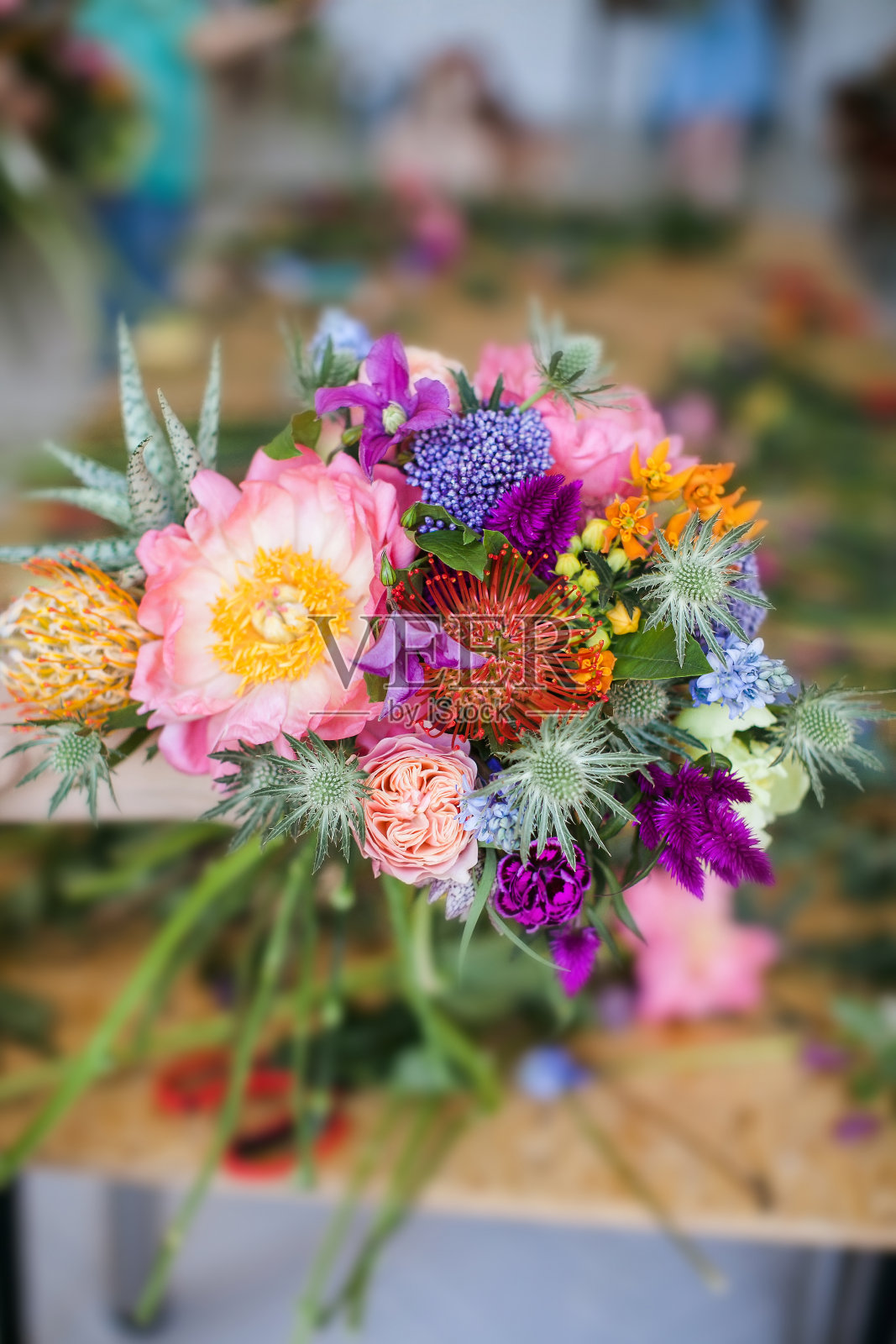 女人手里捧着一束白花、牡丹、风信子等花。教育。花商与顾客沟通在车间在工作室用鲜花。照片摄影图片