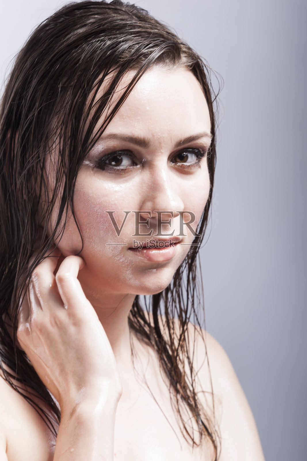 美丽的概念和理念。白人感性的深色头发触摸脖子的特写肖像,显示湿和闪亮的皮肤和湿头发。创意化妆。针对灰色。垂直的图像组成照片摄影图片