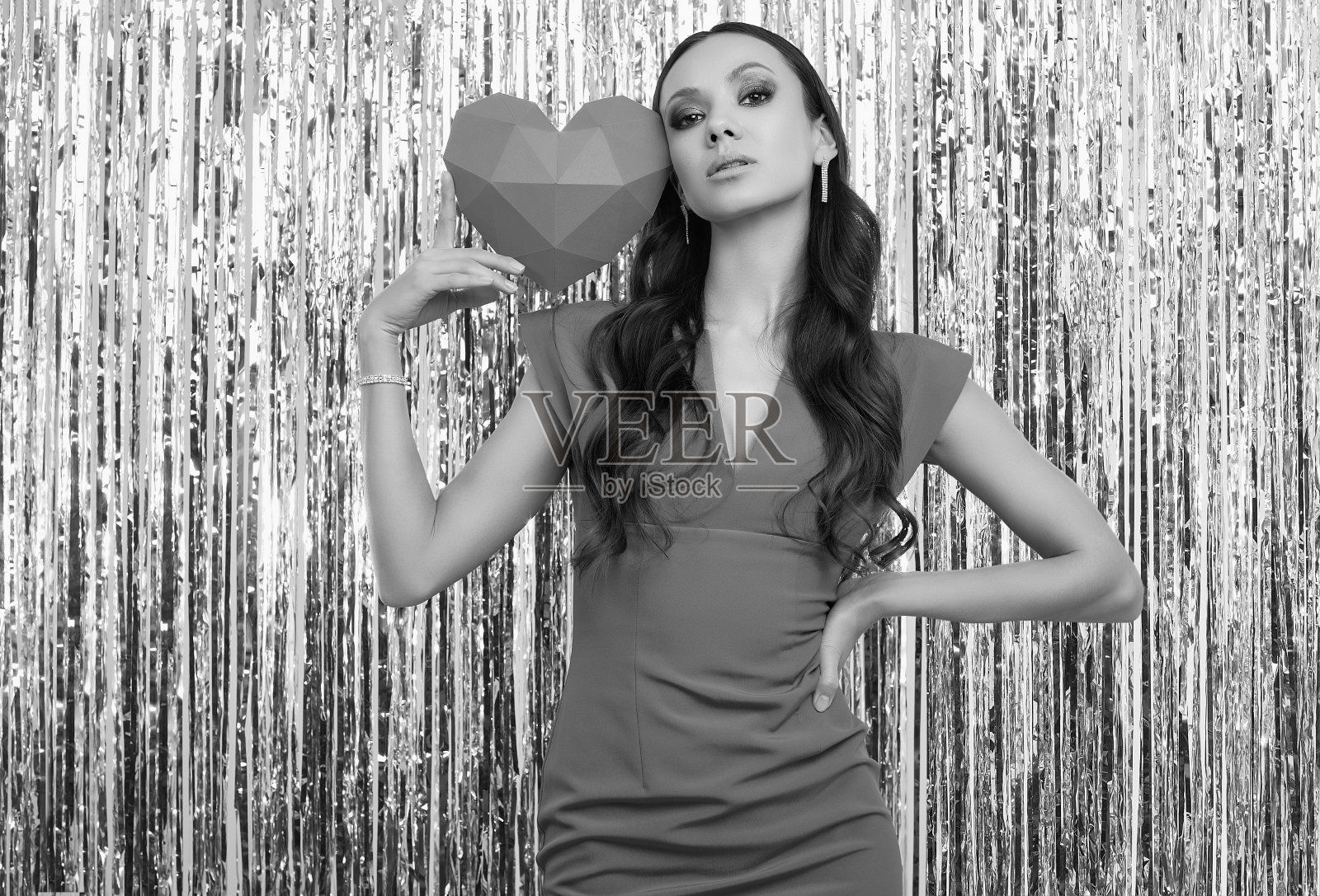 身穿奢华红裙的优雅西班牙裔黑发女人手持纸质心形照片摄影图片