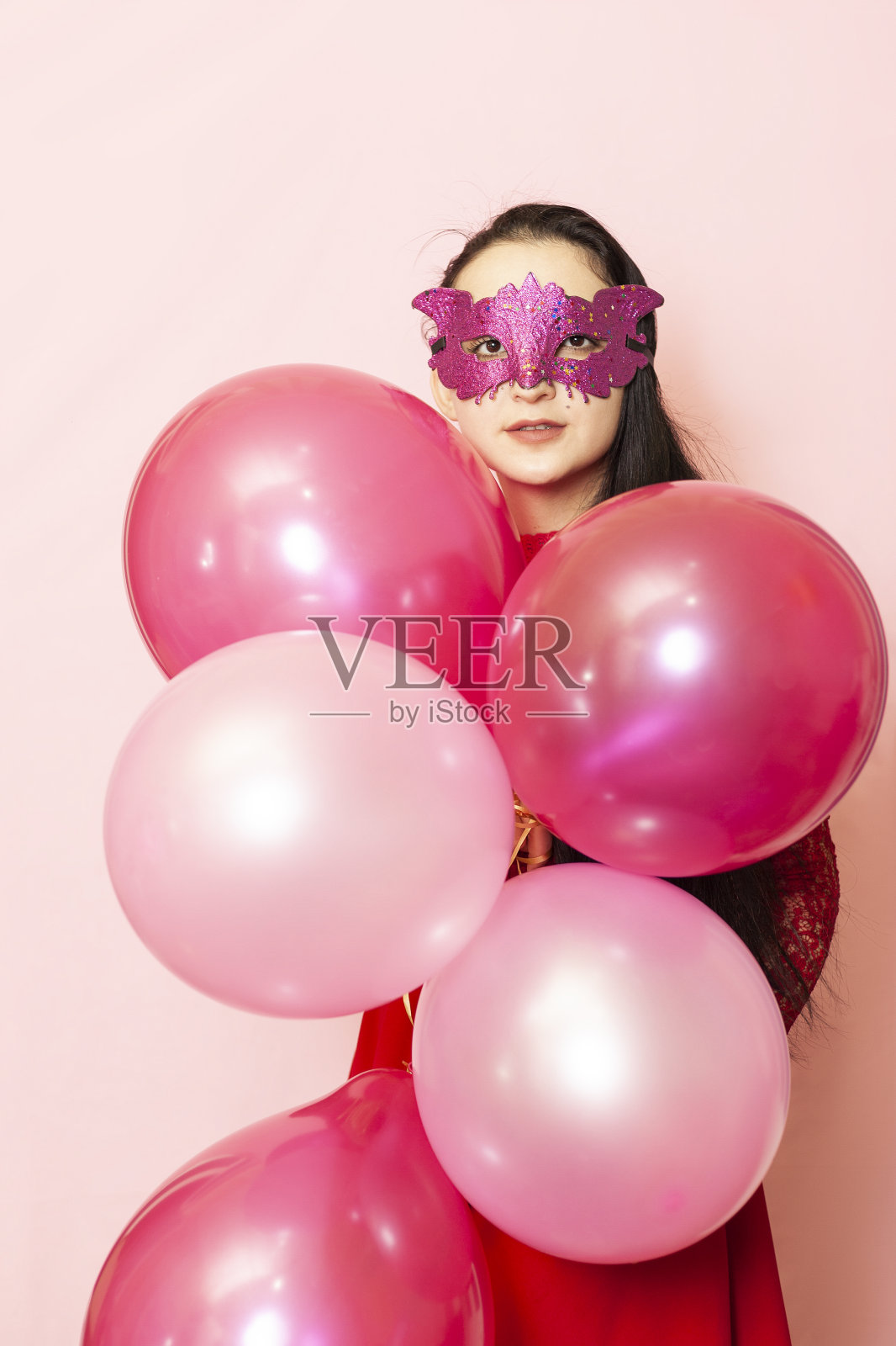 年轻漂亮的女人戴着面具拿着节日的气球。肖像快乐的20岁中东女性庆祝情人节,生日,派对照片摄影图片