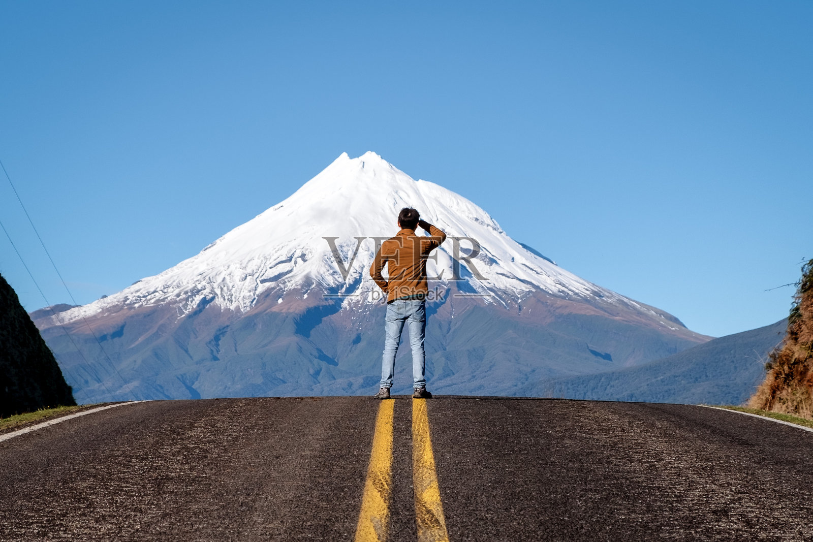 一名男子站在新西兰塔兰基山顶的公路顶上。照片摄影图片