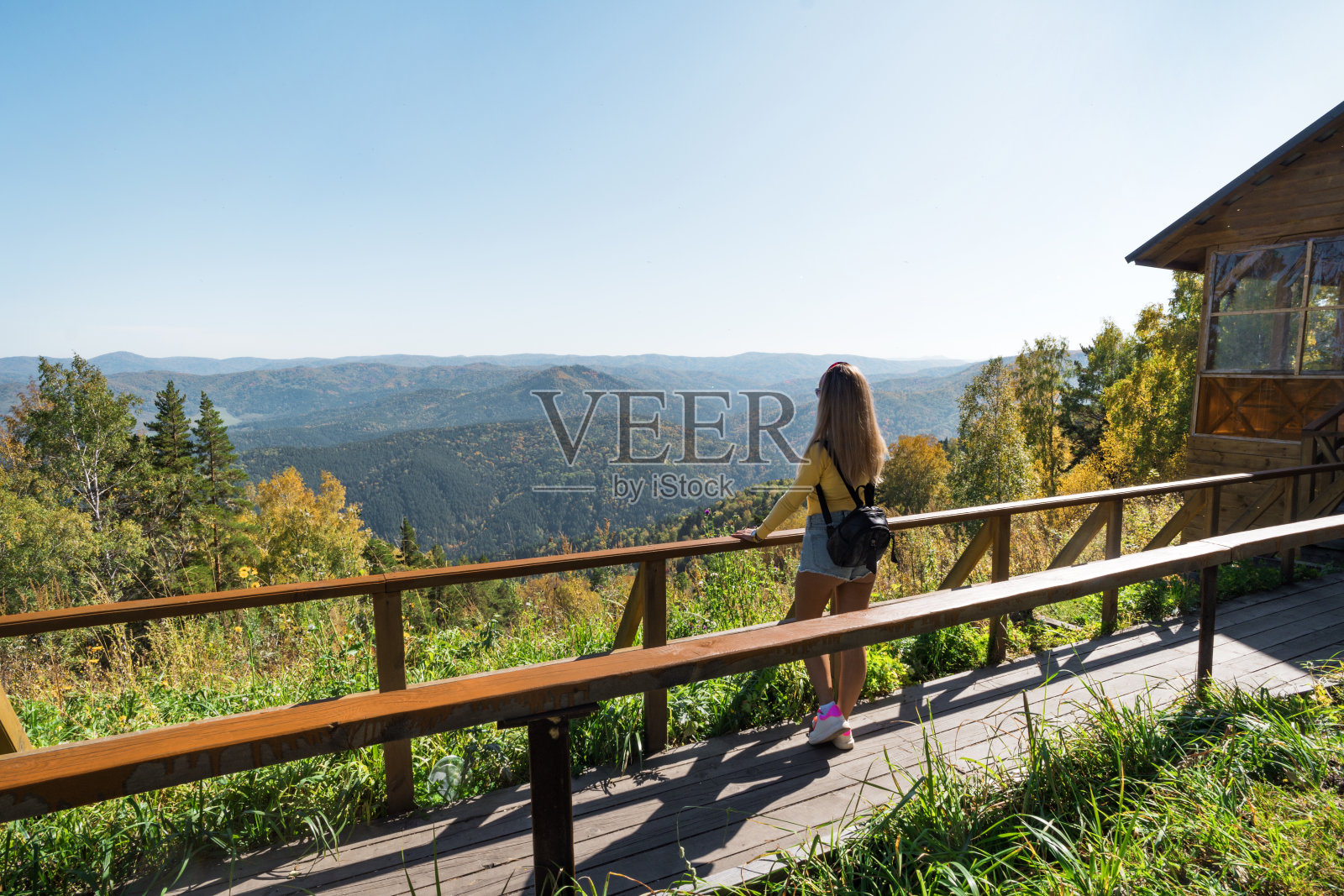 游客女孩站在教堂山坡上俯瞰度假小镇,欣赏山上的美丽景色照片摄影图片