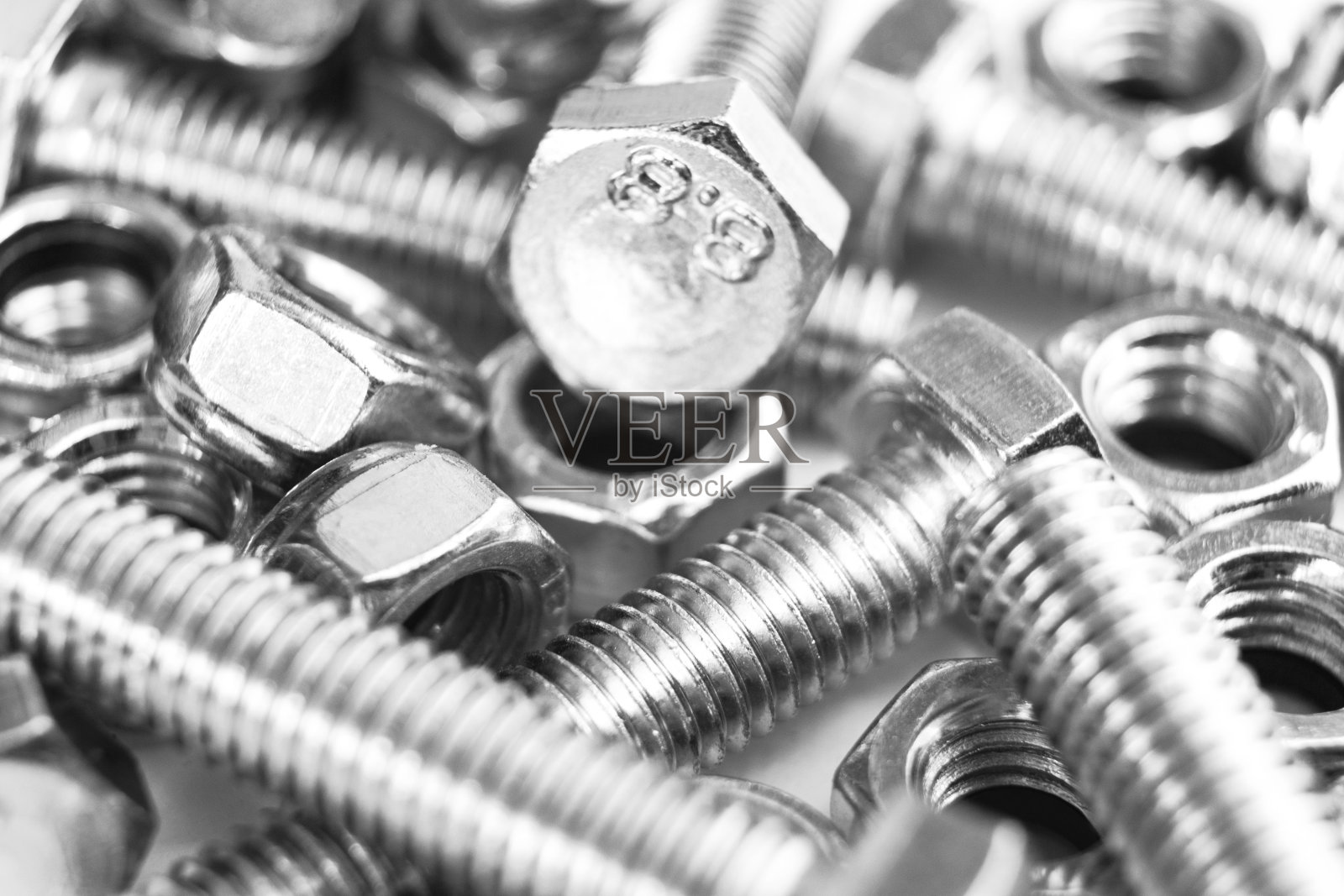 金属螺栓和螺母在一排背景。镀铬螺栓和螺母隔离。钢螺栓和螺母模式。一套螺母和螺栓。工作的工具。黑色和白色照片摄影图片