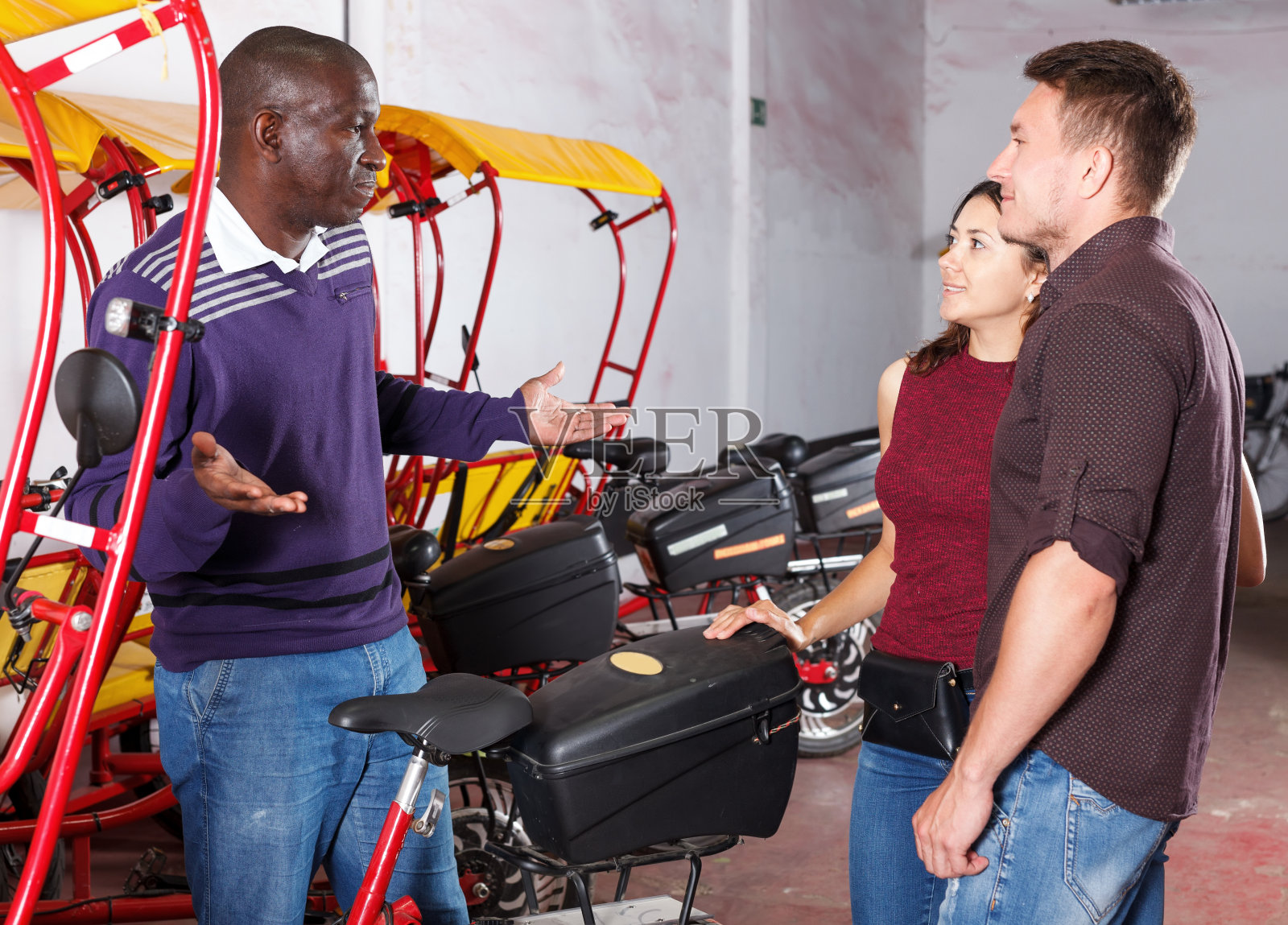 与年轻夫妇交谈的非裔美国人力车夫照片摄影图片