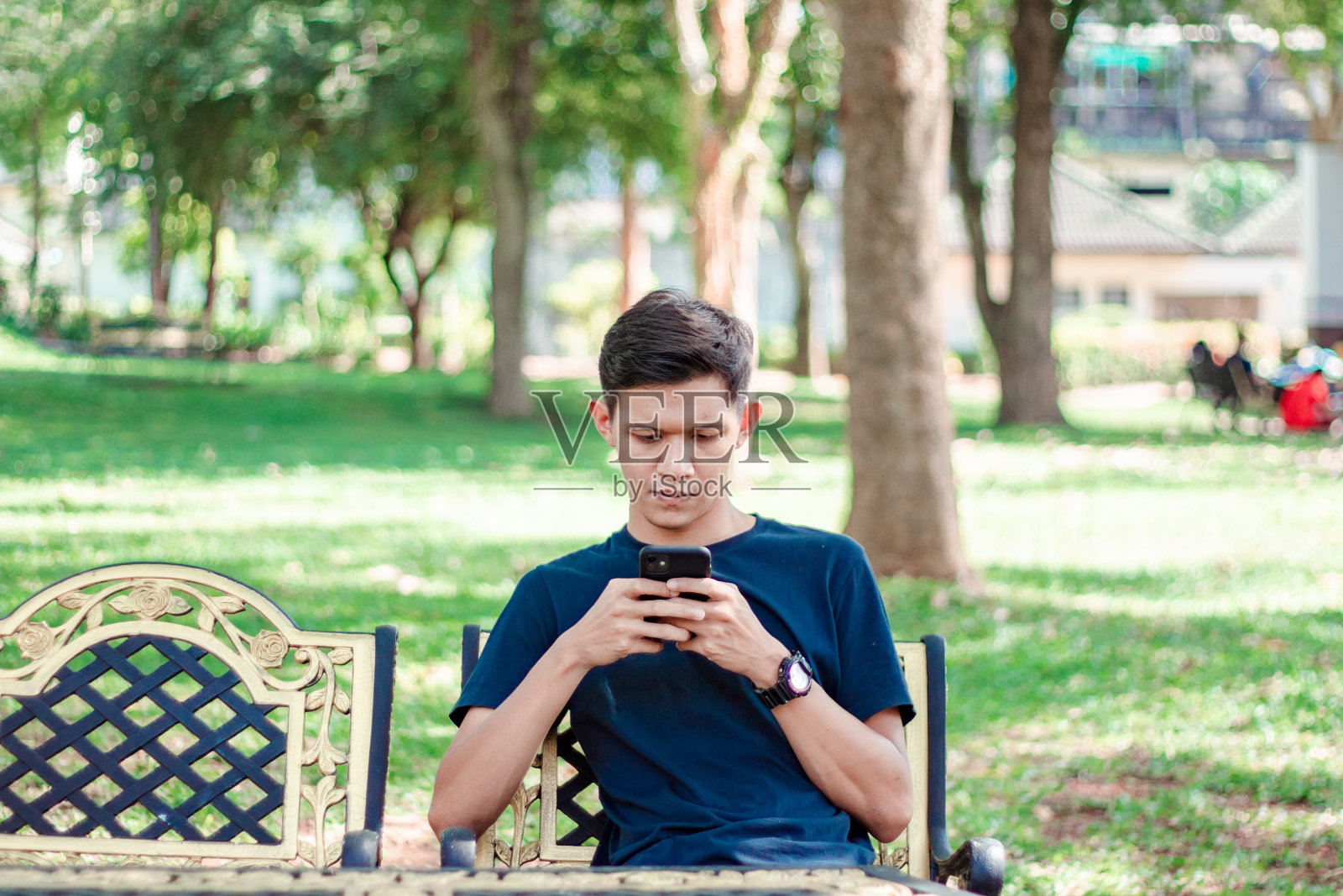 亚洲男人在公园里用智能手机照片摄影图片