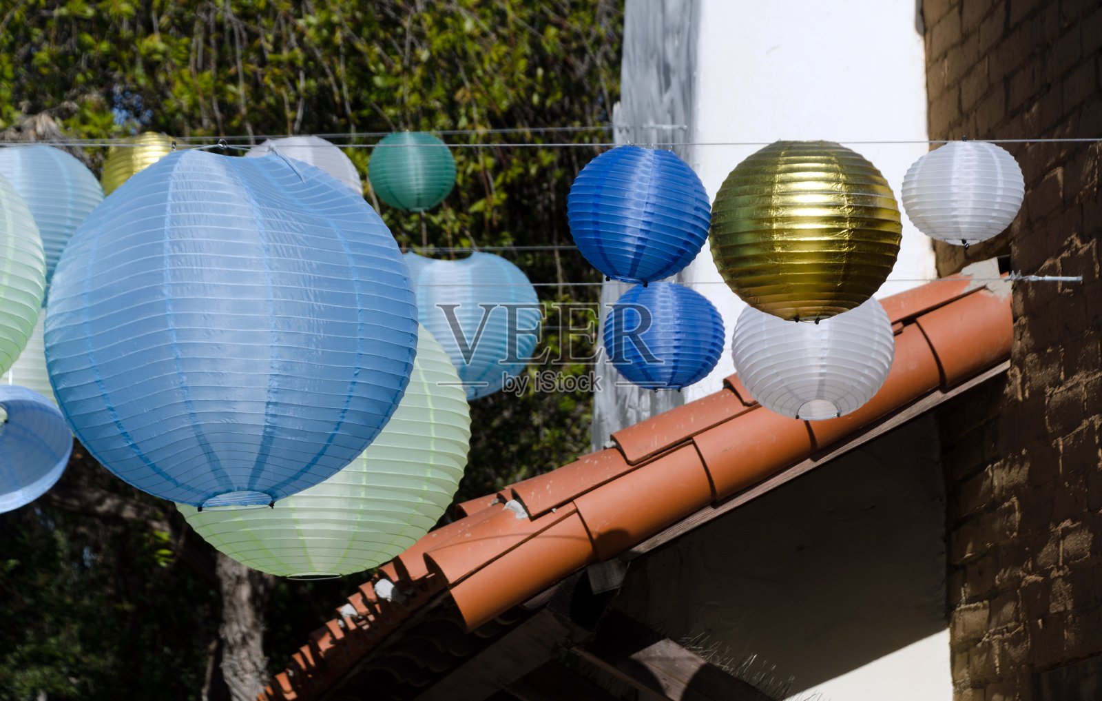 圣诞节期间,蓝色、绿色和金色的灯笼装饰着海港村,背景是瓦片屋顶照片摄影图片