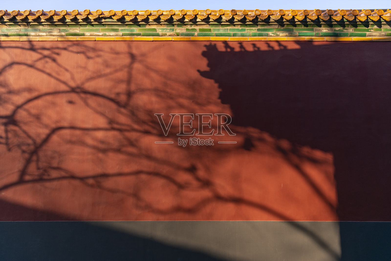 中国北京紫禁城红宫墙和装饰瓦屋顶上的树木和建筑阴影照片摄影图片