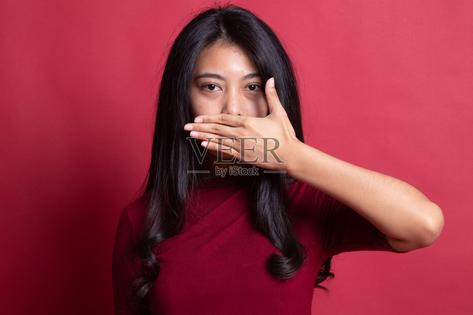 年轻的亚洲女子用手闭上了嘴。照片摄影图片