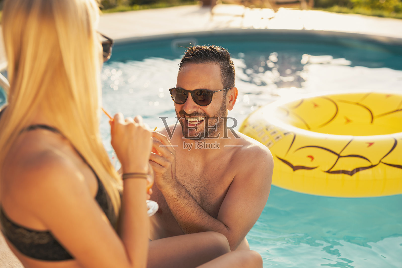 一对情侣在游泳池边喝鸡尾酒照片摄影图片