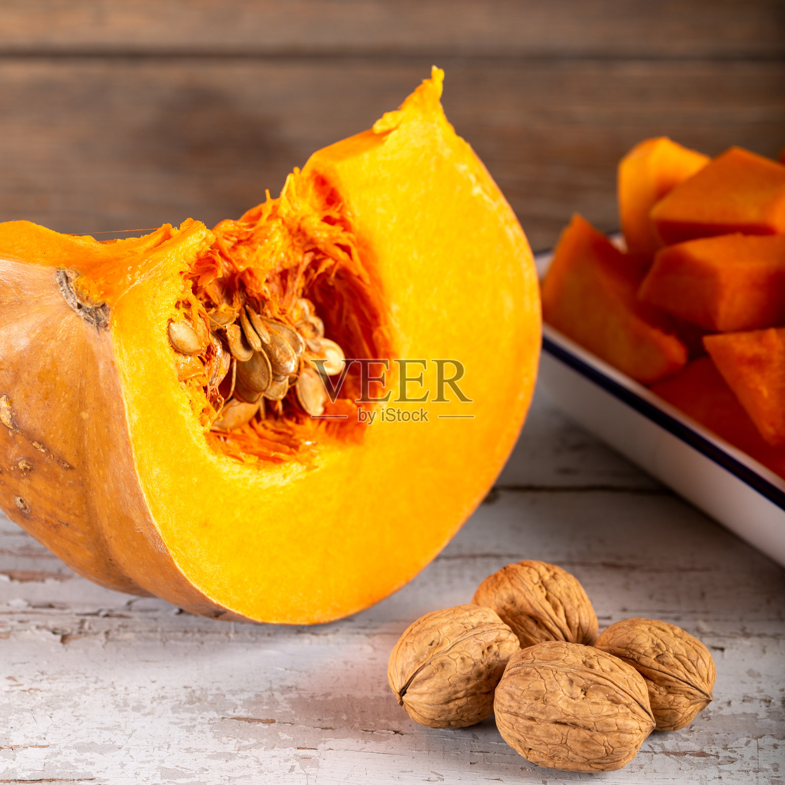 削皮并切碎的南瓜和核桃在木制的背景。照片摄影图片