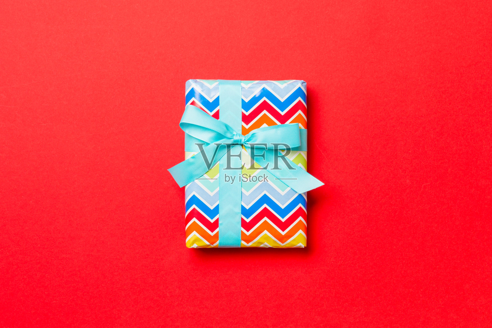 用红底蓝丝带纸包好的圣诞节或其他节日手工礼品。礼品盒,彩桌上礼品装饰,顶视图有拷贝空间照片摄影图片