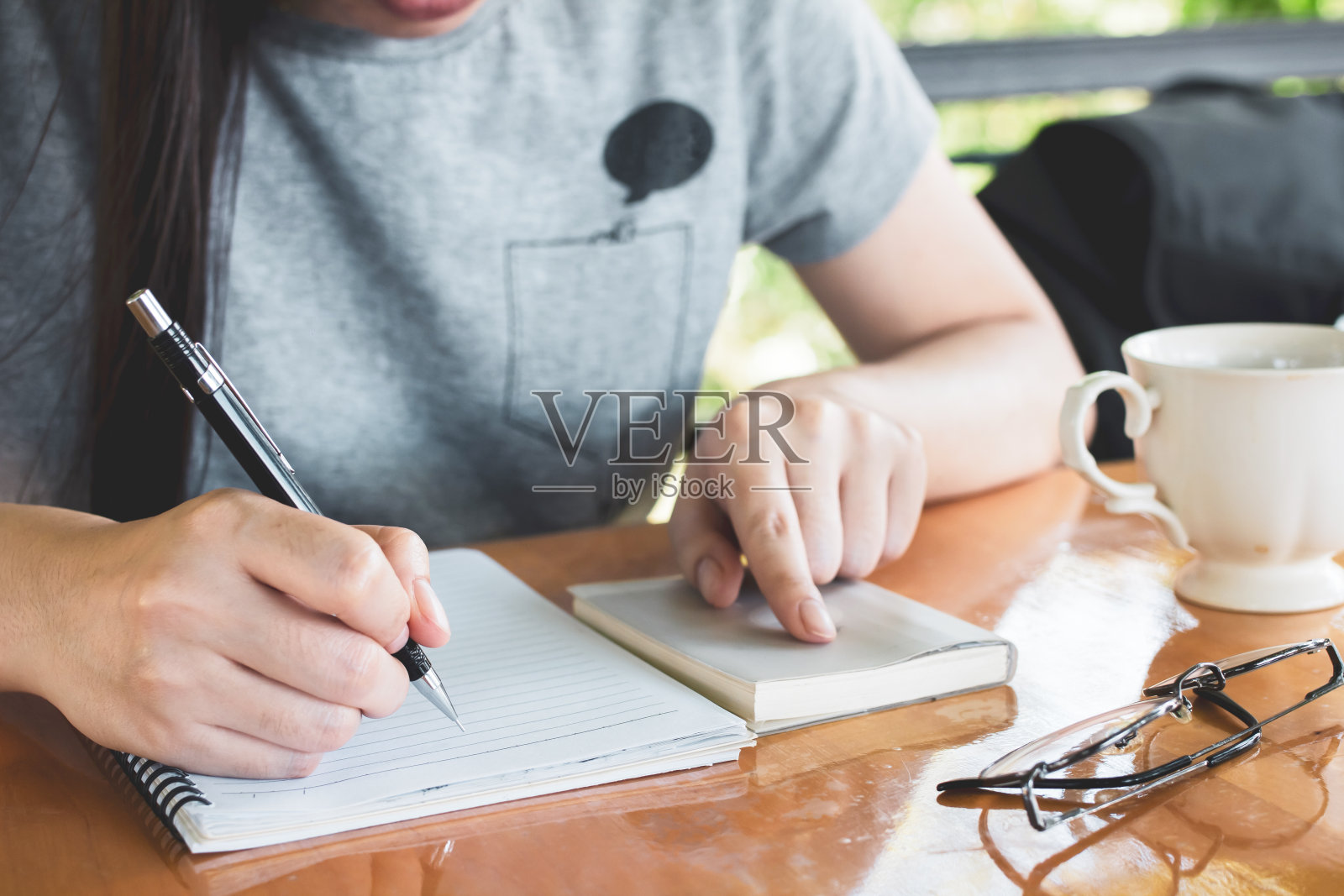 女人早上在咖啡馆书写,有咖啡和眼镜照片摄影图片