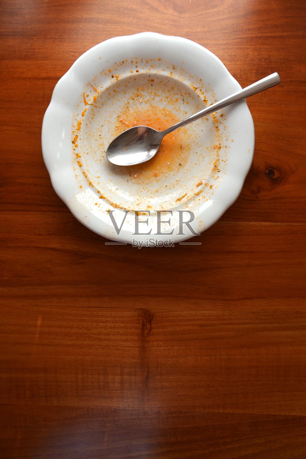 木桌上放空白色盘子和勺子,平放俯视图,红色的汤或酱照片摄影图片