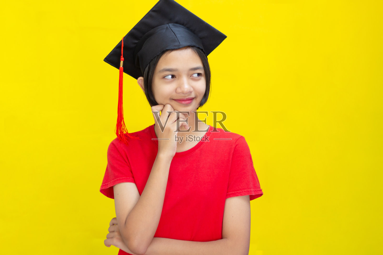 肖像快乐可爱的年轻女孩与复制空间和学术帽。黄色背景。照片摄影图片