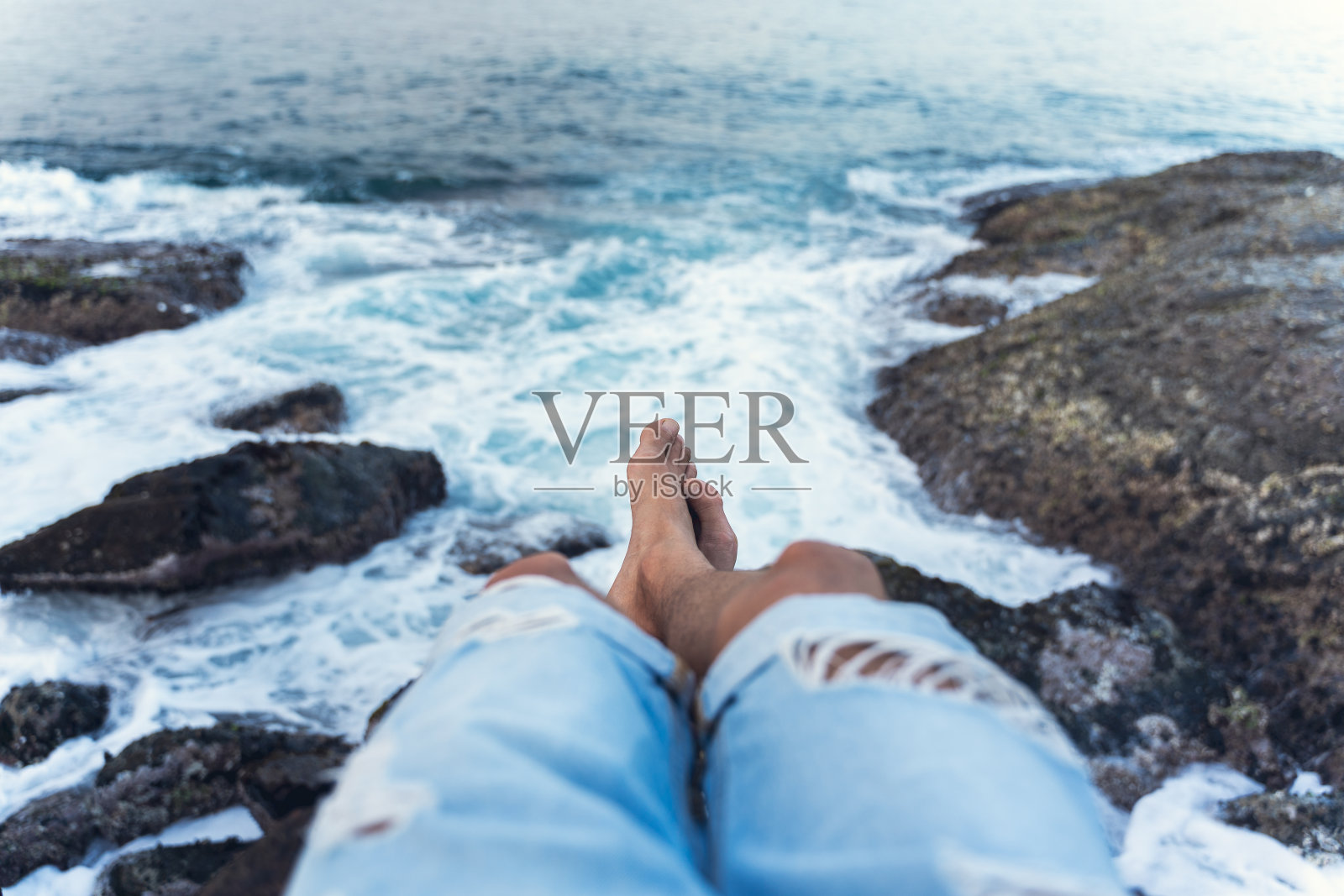 一个年轻人在日落时坐在悬崖上的个人视角照片摄影图片