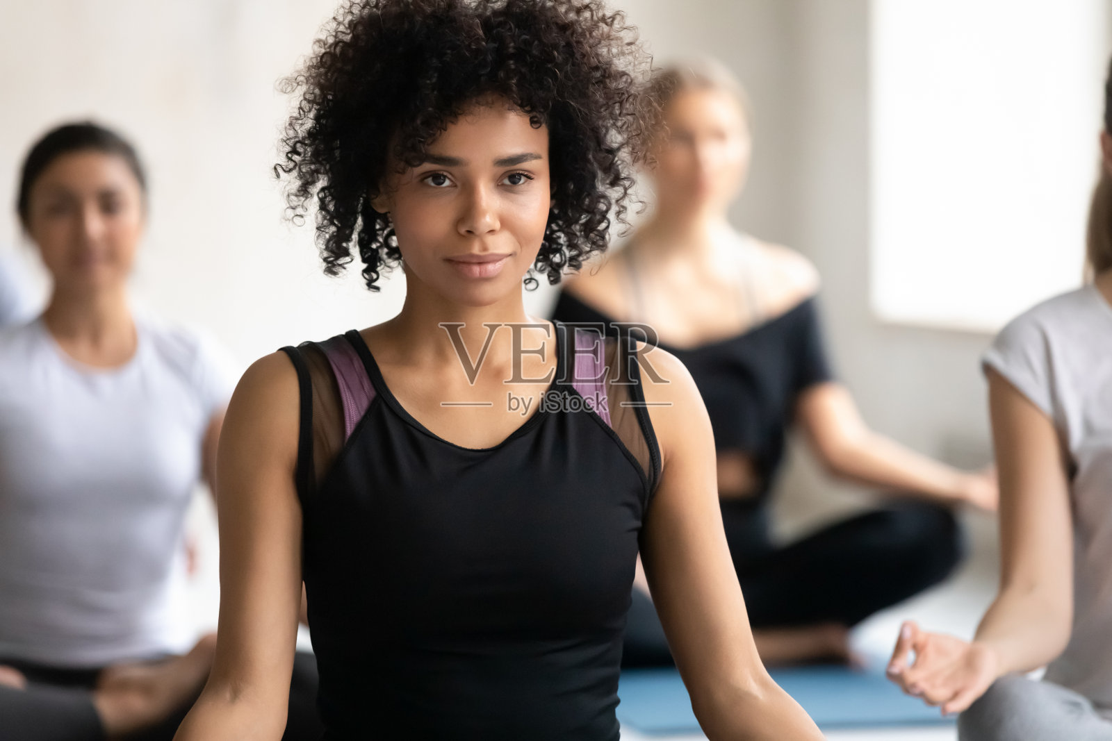 非裔美国妇女练习瑜伽在小组课,莲花身练习照片摄影图片