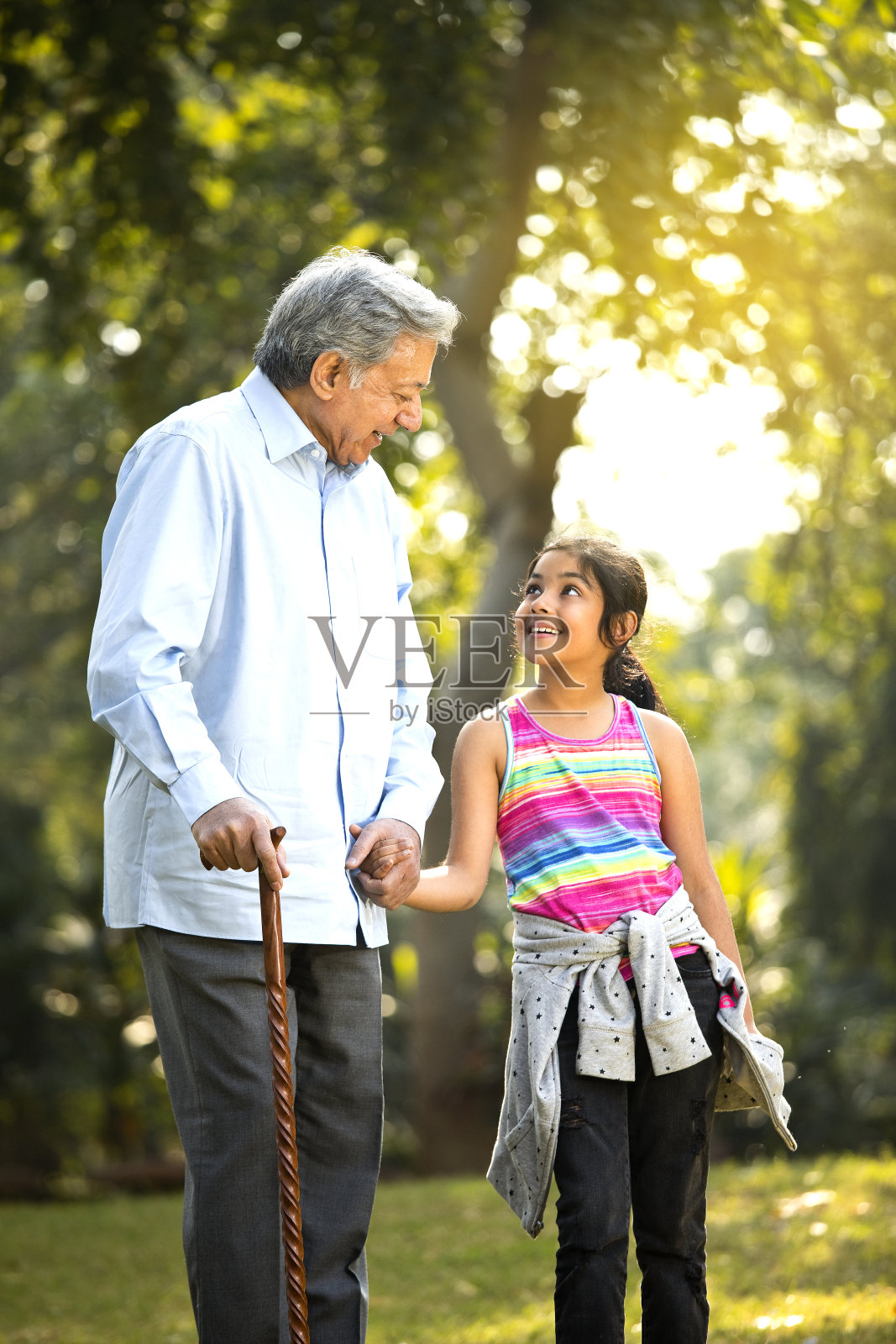 快乐的女孩在公园牵着爷爷的手照片摄影图片