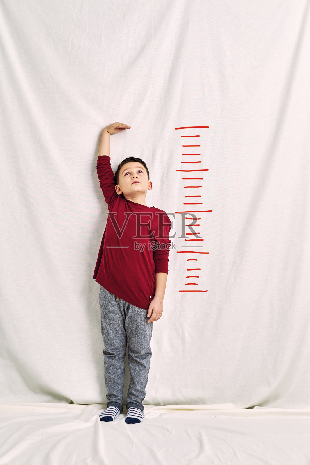 可爱的孩子在测量他的身高。经济增长的概念。照片摄影图片