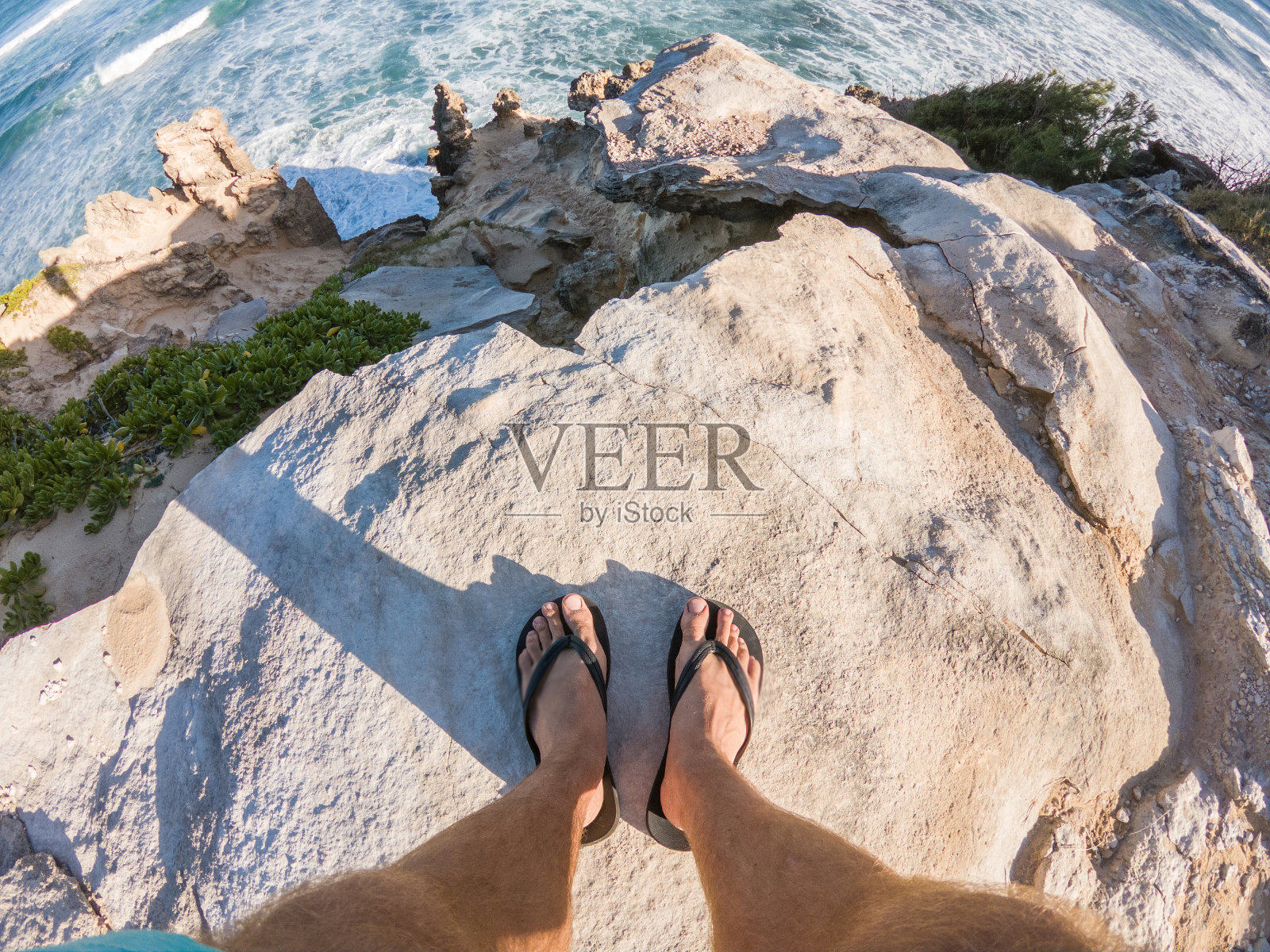 人的脚在岩石海岸线上看海洋的观点照片摄影图片