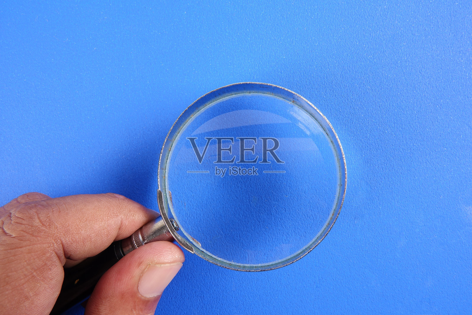 手持放大镜在蓝色背景上照片摄影图片