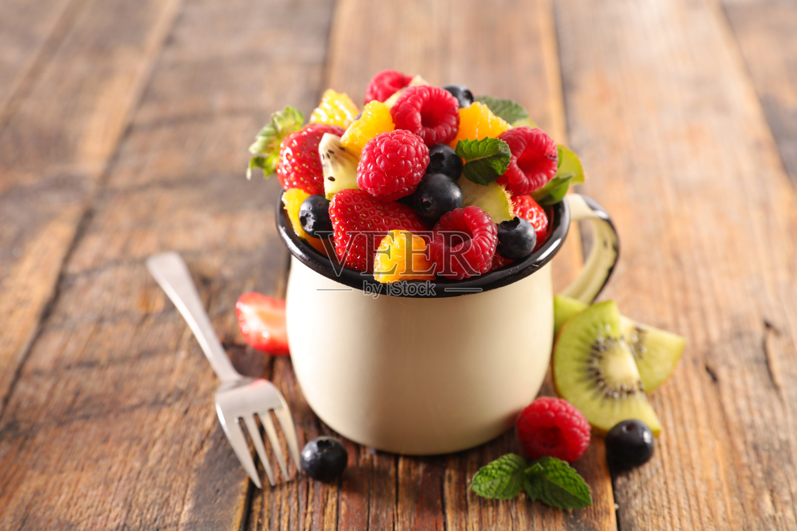 水果沙拉与浆果水果,橘子和猕猴桃在马克杯照片摄影图片