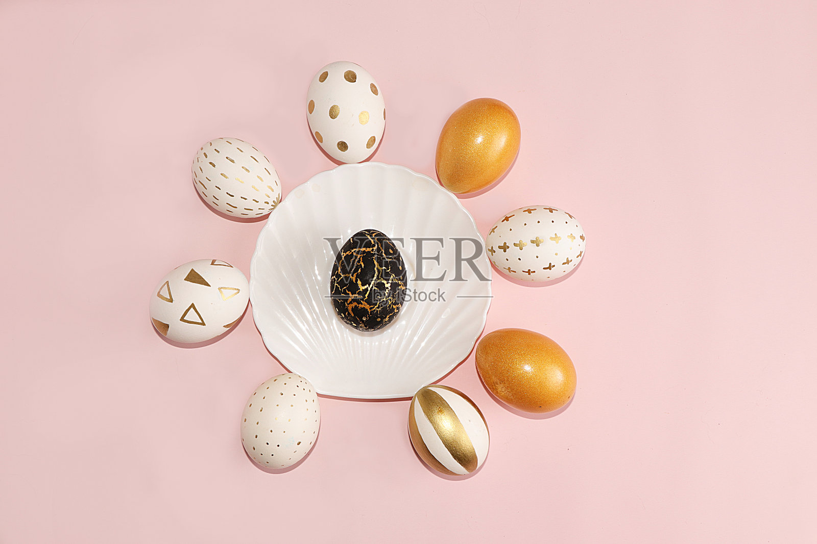 粉红色背景上装饰的金色复活节彩蛋。最小的节日的概念。复活节快乐背景。在家创造性地画鸡蛋。照片摄影图片