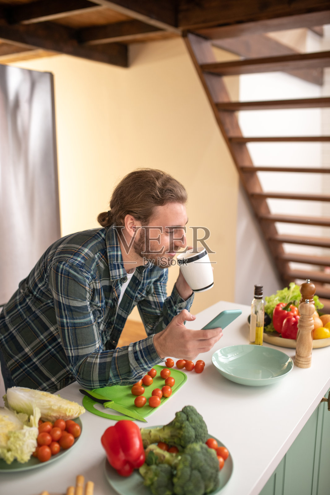 微笑的男人一边喝茶一边做饭一边发短信照片摄影图片