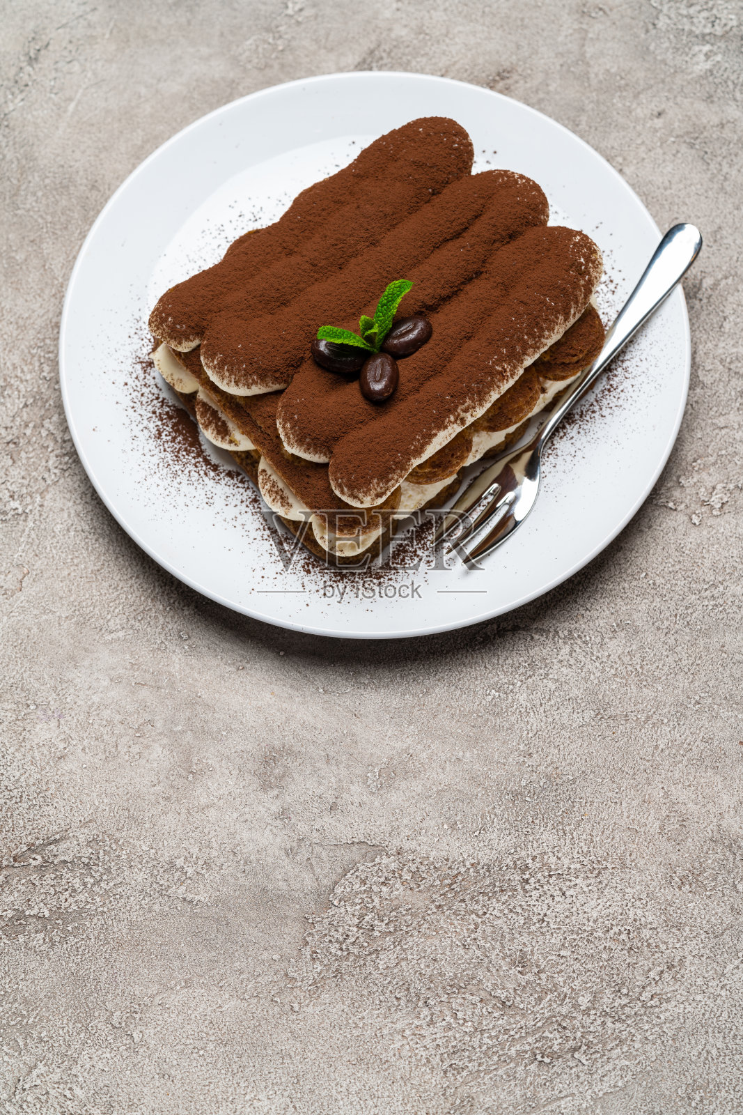 经典的提拉米苏甜点在浅灰色混凝土背景的陶瓷板上照片摄影图片