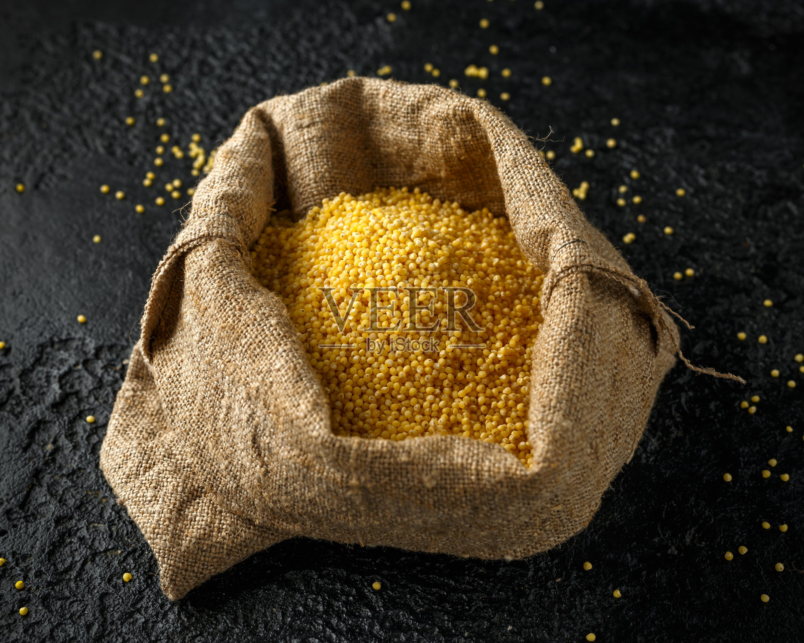 小米谷粒倒入粗麻袋、袋装。有机概念照片摄影图片