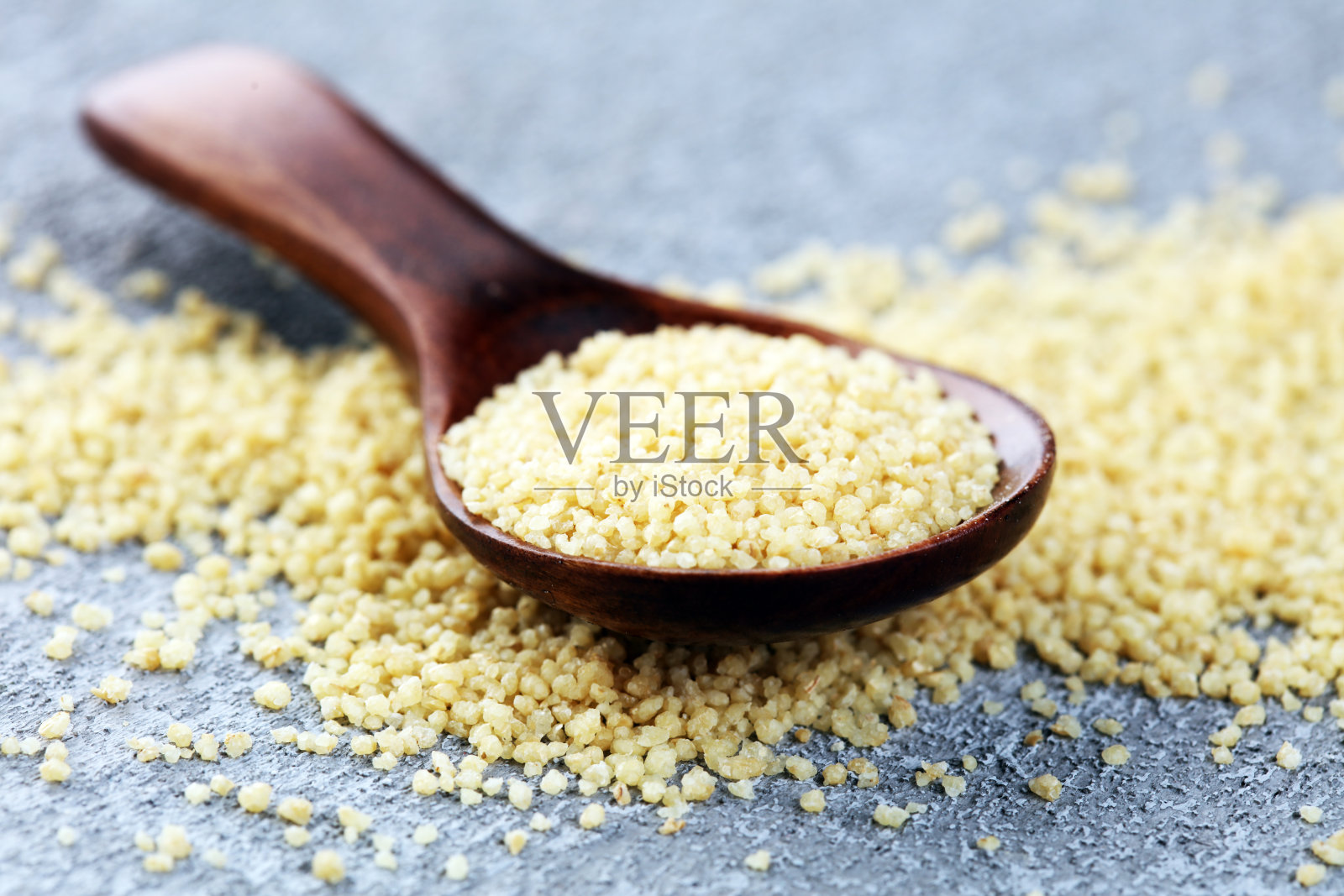 用木勺盛着蒸粗麦粉。健康的食物照片摄影图片