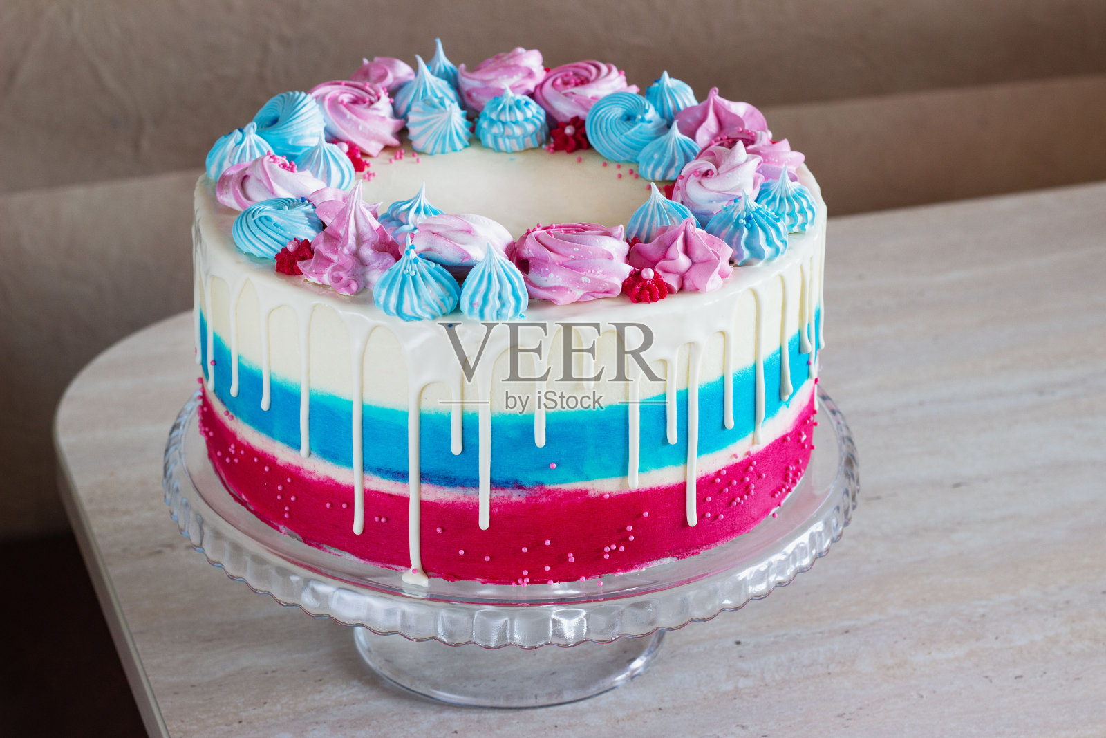 明亮的节日蛋糕与多种颜色的蛋白霜在桌子上,在一个明亮的背景,节日性别的未出生的孩子照片摄影图片