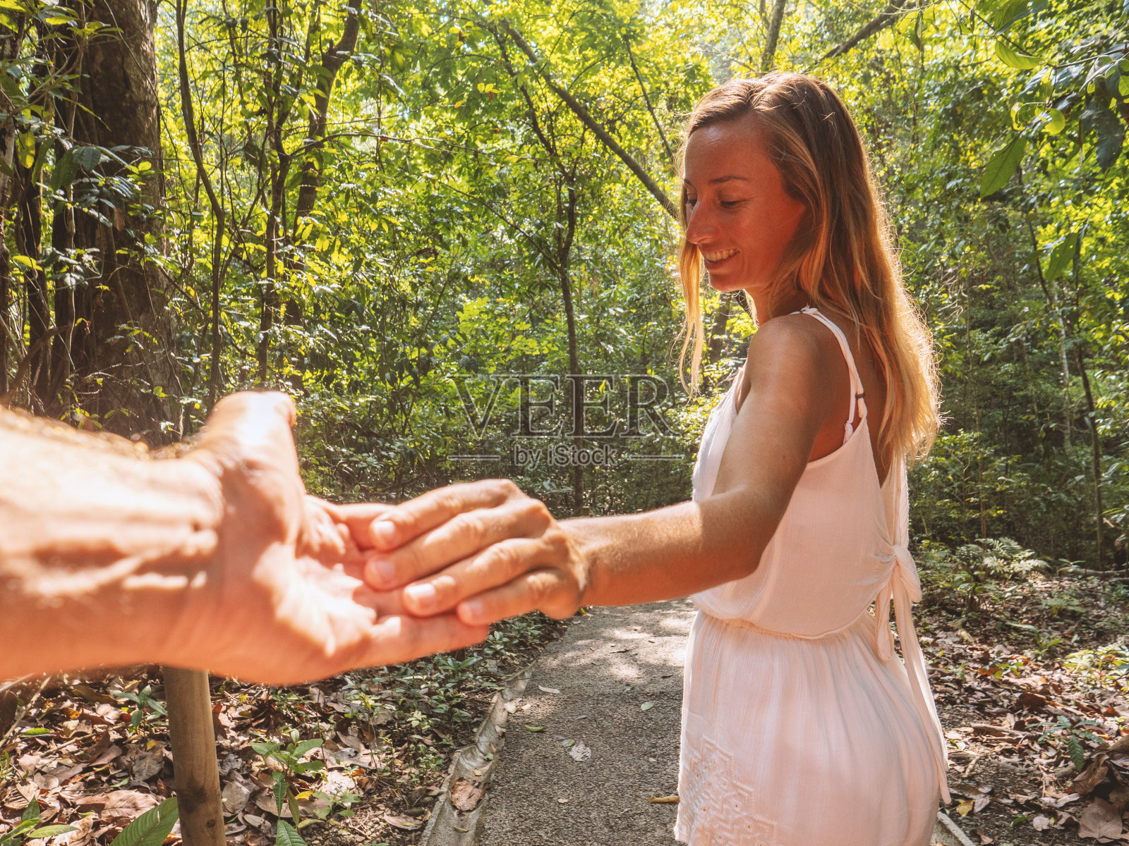 “跟我来”概念:年轻女子带领男友走向热带雨林照片摄影图片