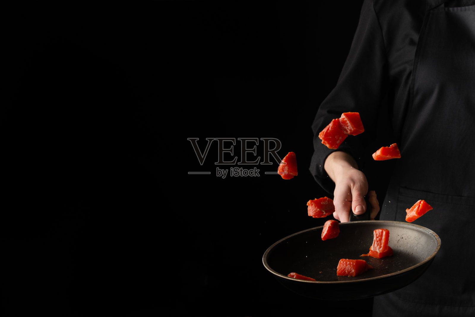 海鲜烹饪:厨师在平底锅中煎三文鱼照片摄影图片