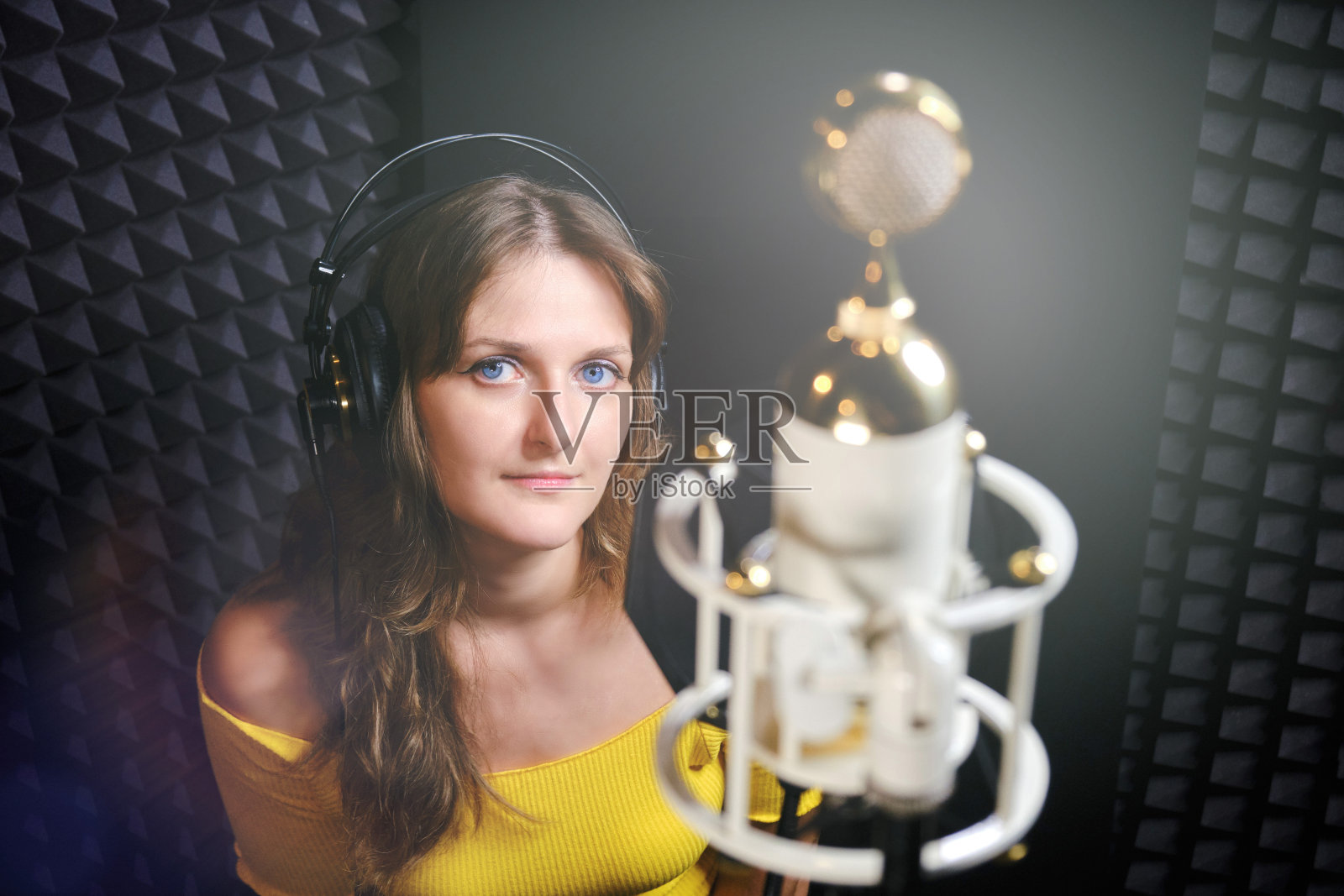 在录音室用白色麦克风录音的年轻女人照片摄影图片