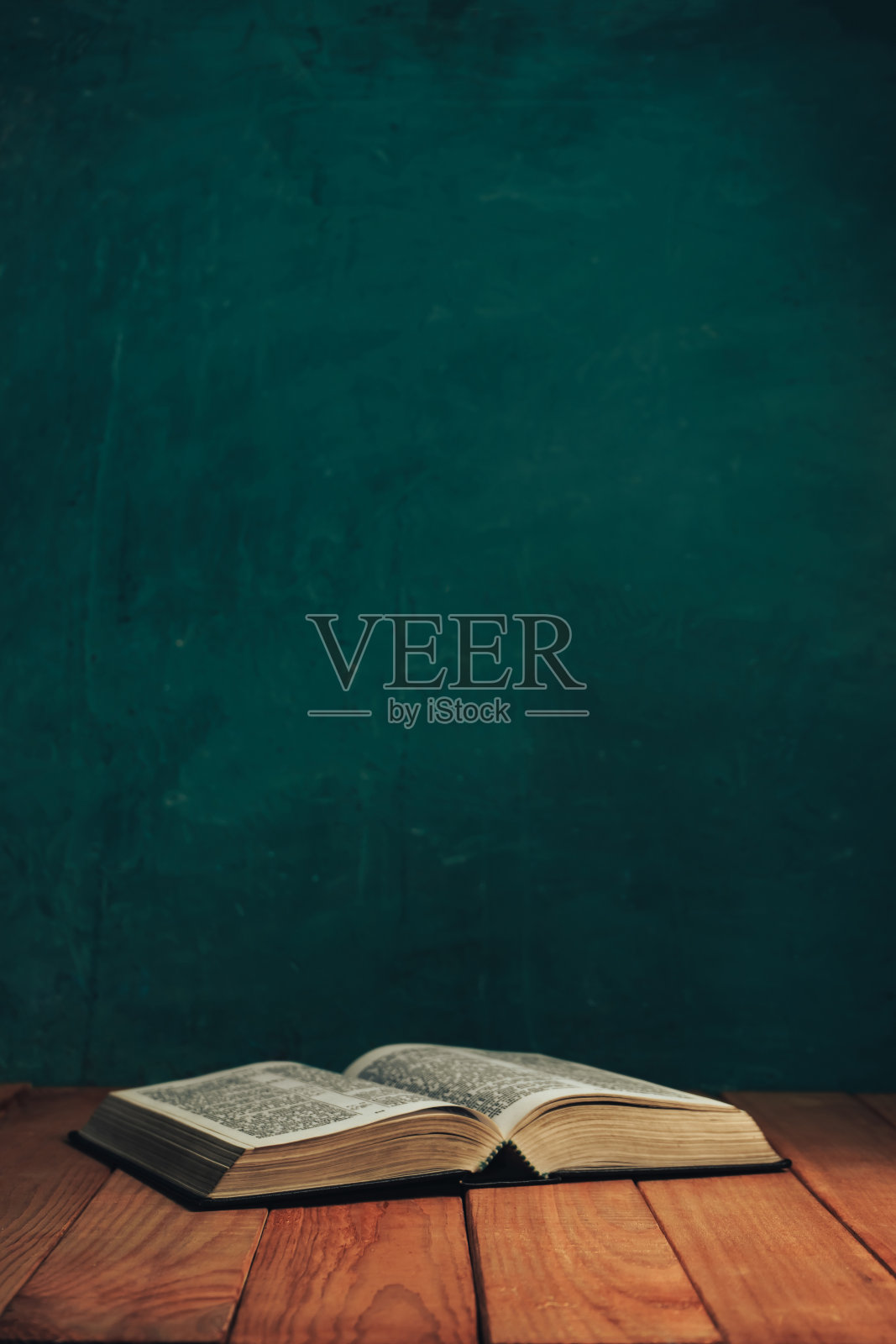 在旧的红色木桌上打开《圣经》。美丽的绿色墙背景。照片摄影图片