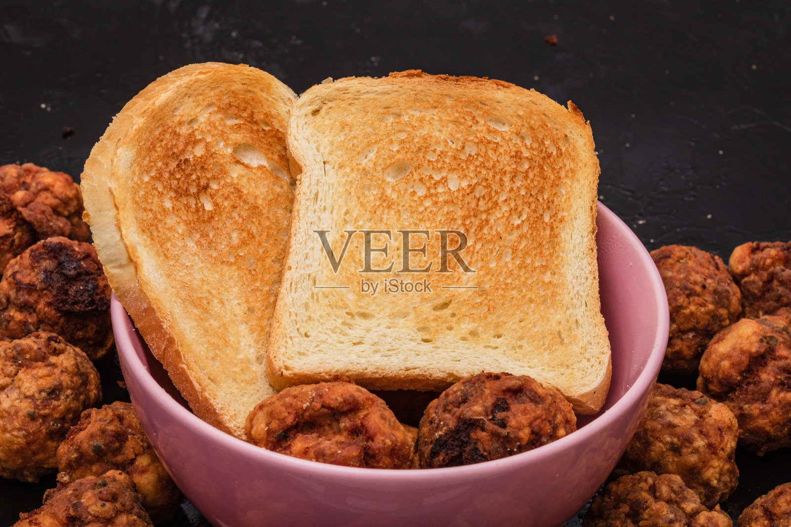 粉红色的碗,配上香料炸肉丸和炸面包。自制的食物。照片摄影图片