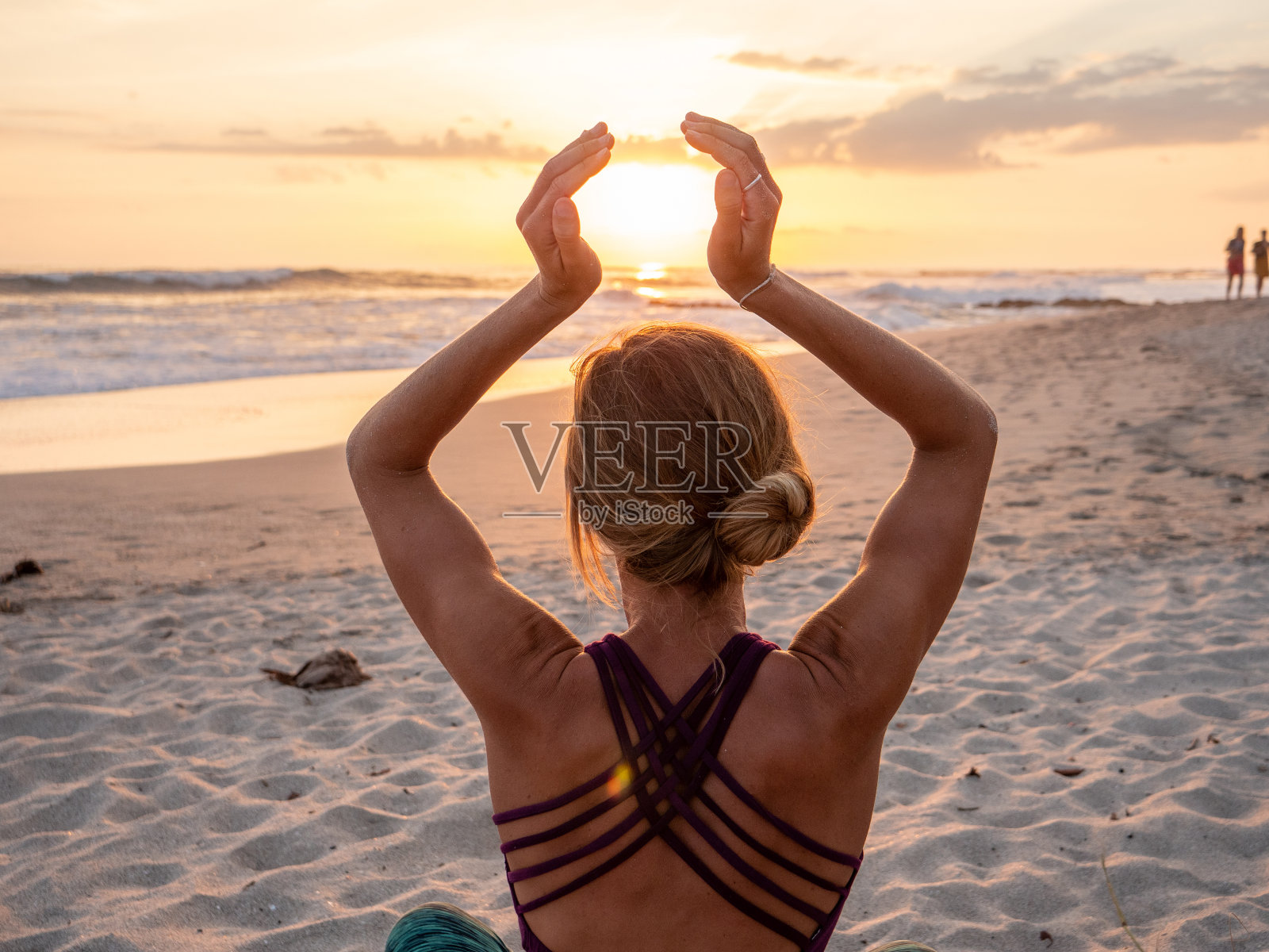 年轻女子在海滩日落时练习瑜伽照片摄影图片