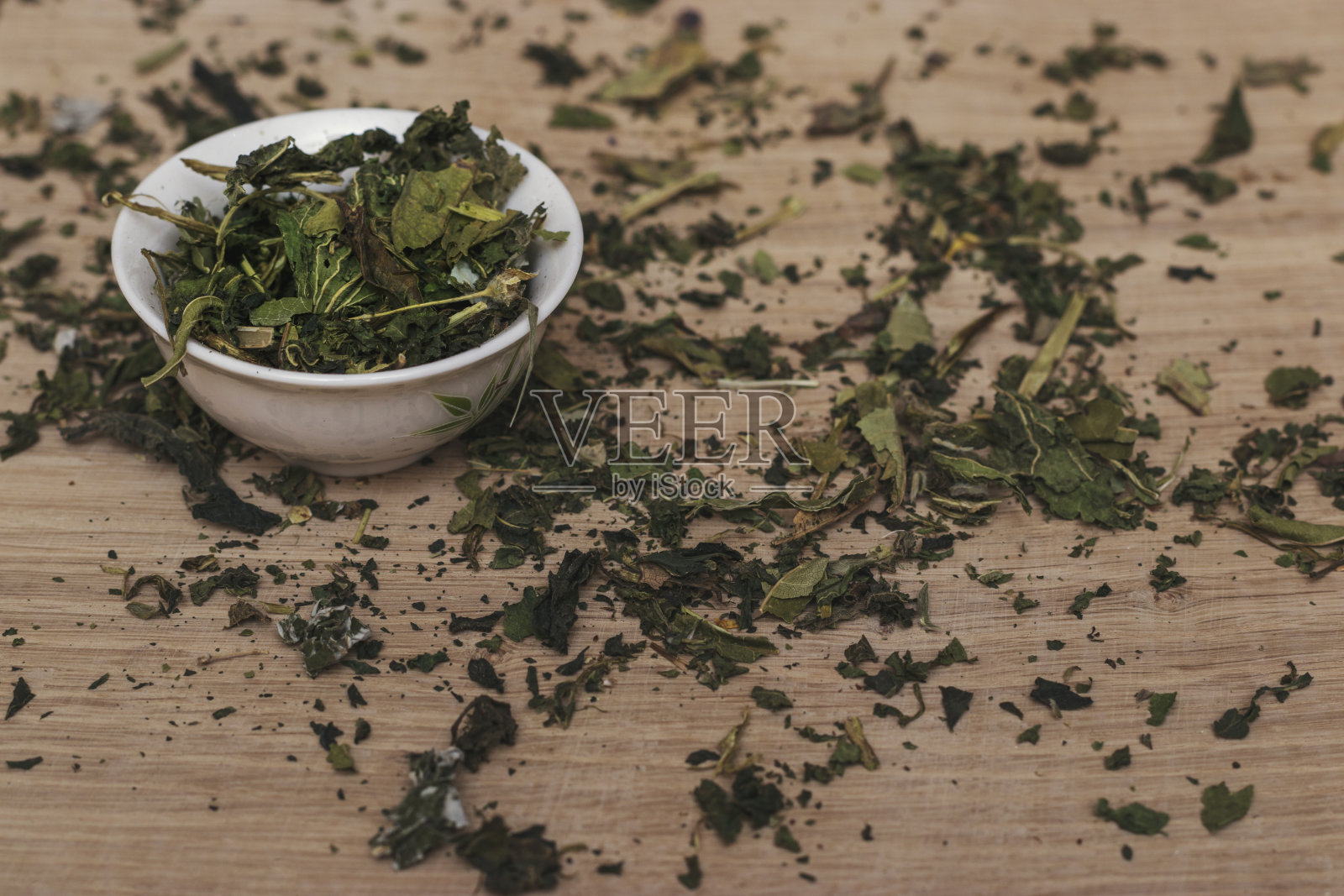 干草撒在白橡木板上,倒进一个白色的碗里。照片摄影图片