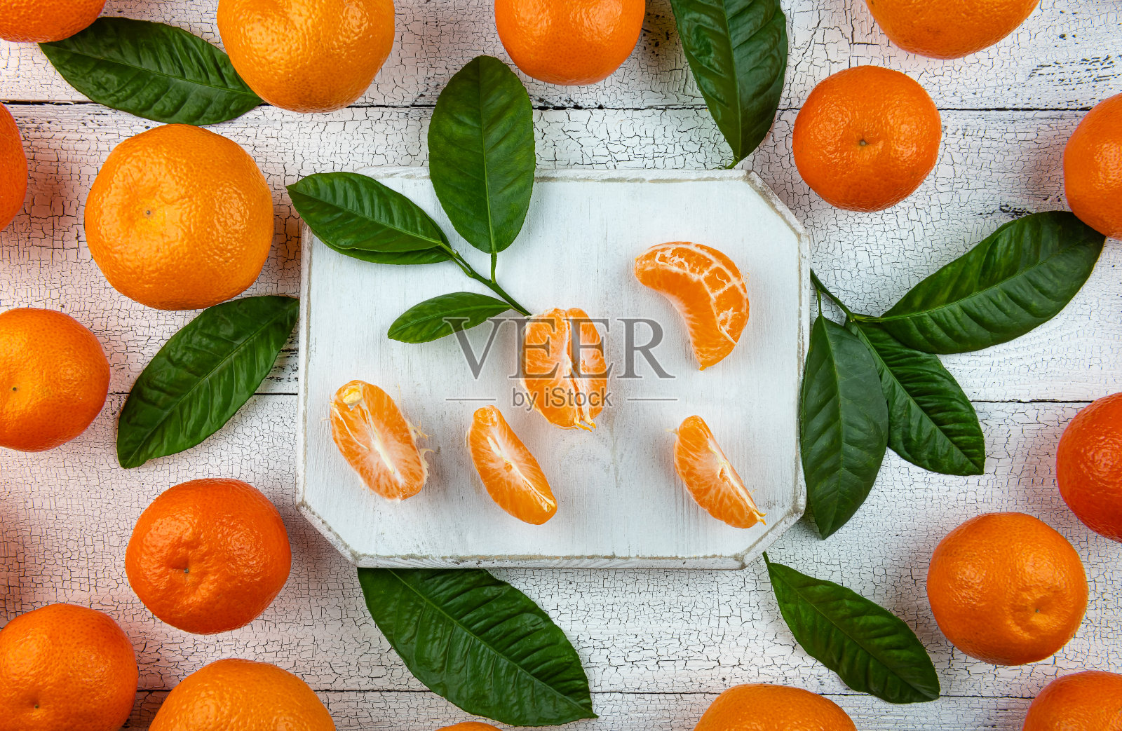 白桌上的橘子瓣和叶子照片摄影图片