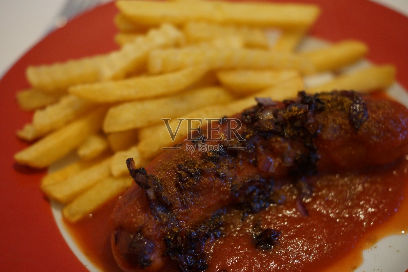 红盘子里的咖喱香肠和薯条照片摄影图片