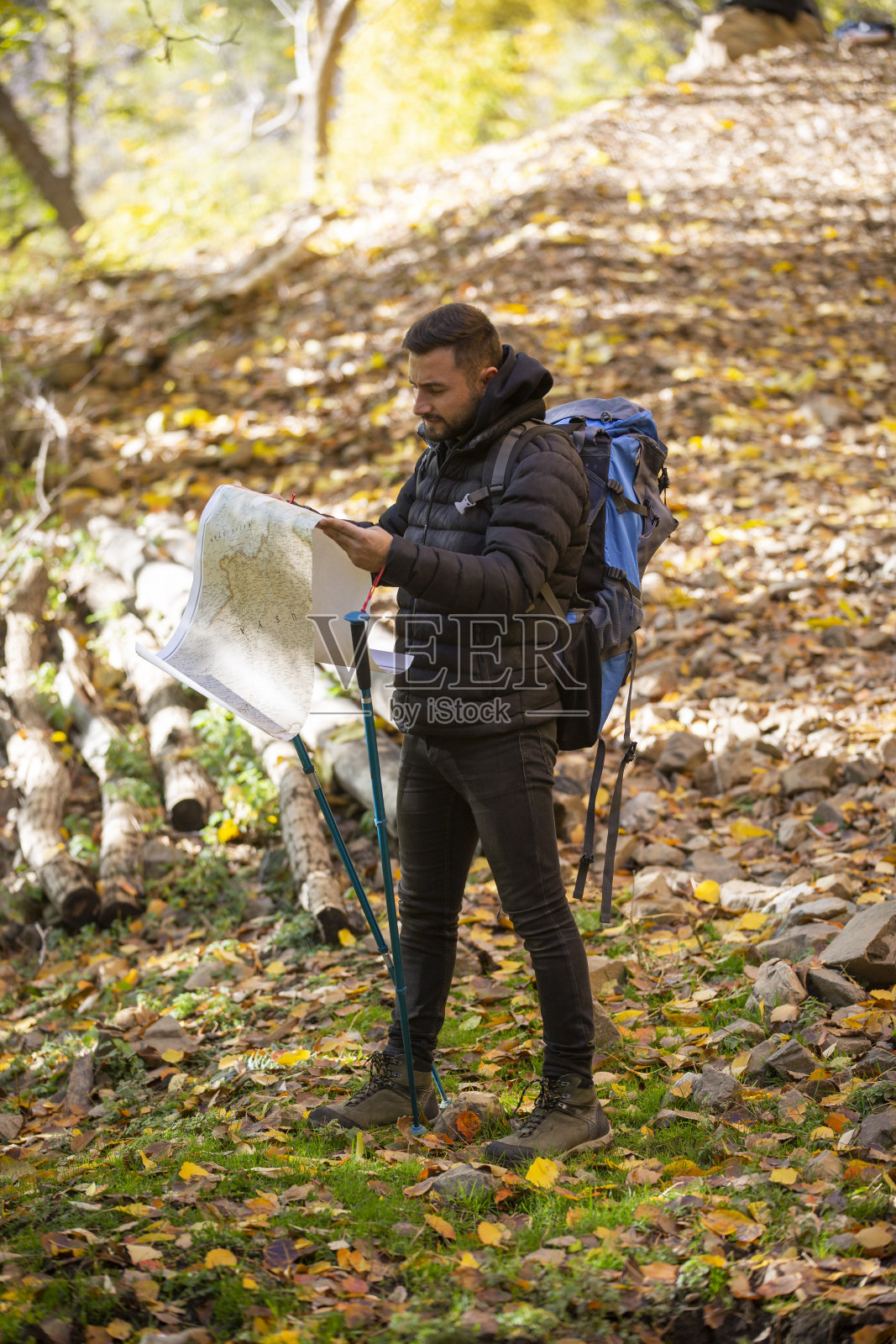 一个坚定的年轻人拿着地图,望着远方,在森林里徒步旅行照片摄影图片