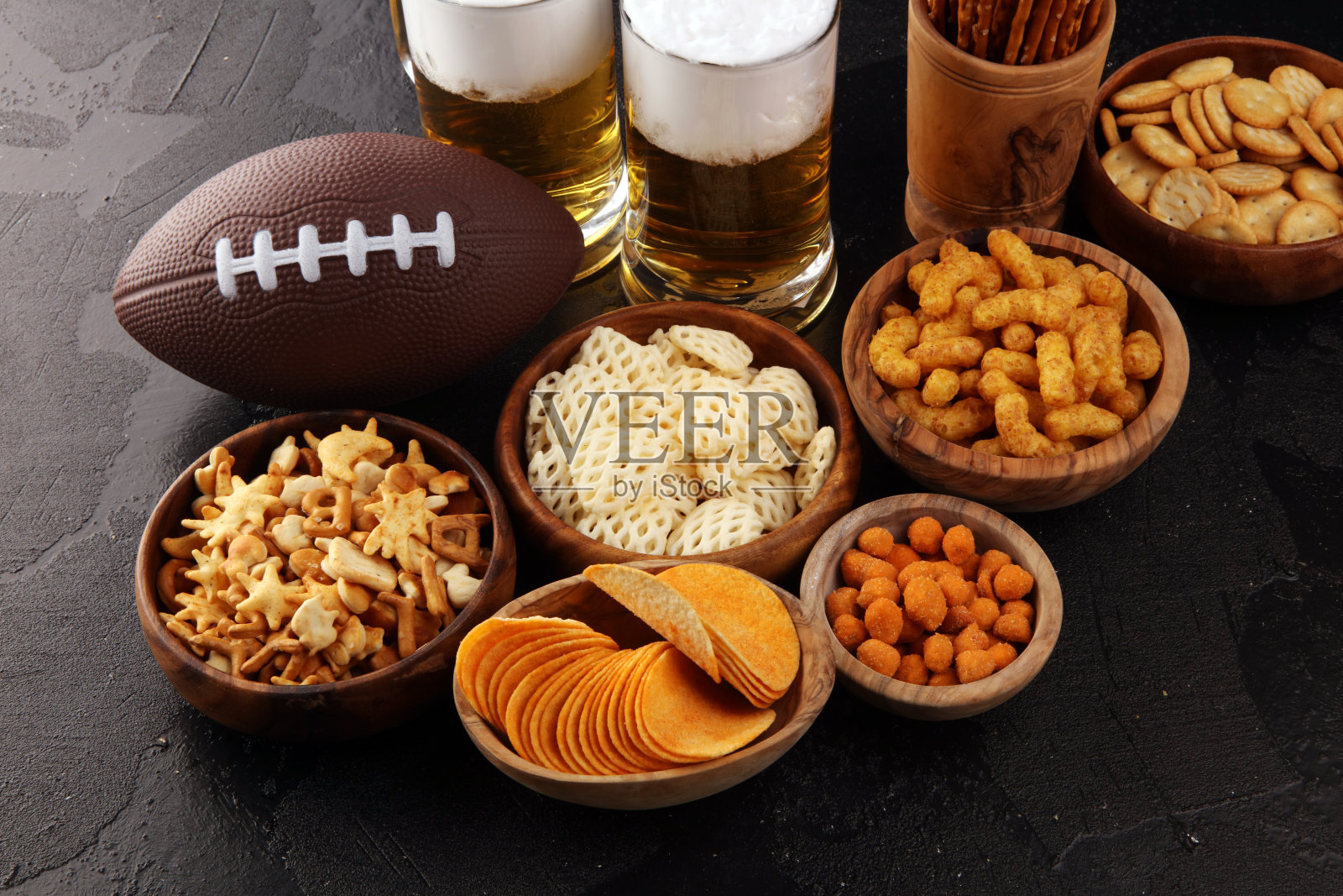 桌上放着薯条、咸味小吃、足球和啤酒。非常适合碗游戏零食项目。照片摄影图片