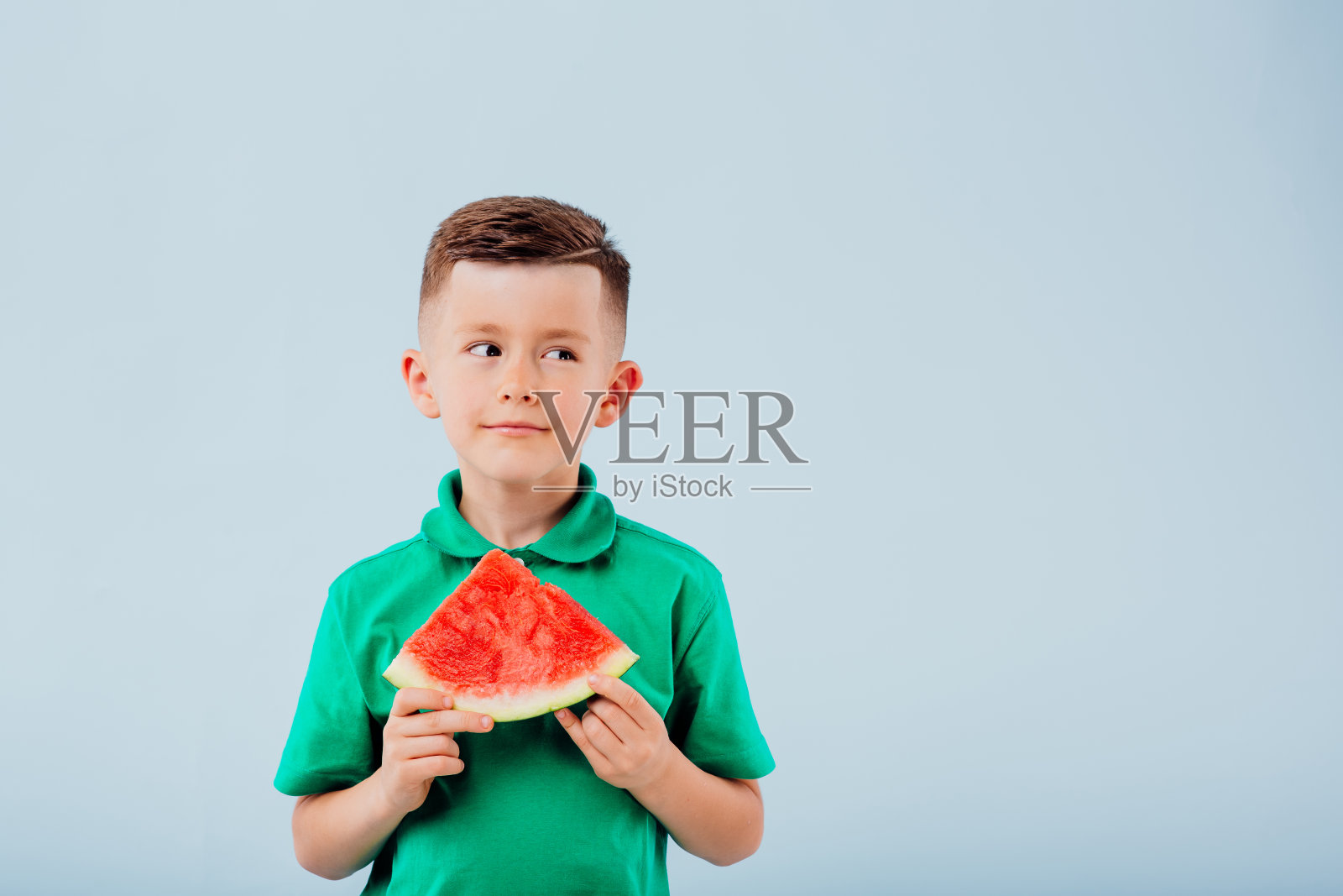 手拿西瓜片,面带笑容的小男孩照片摄影图片